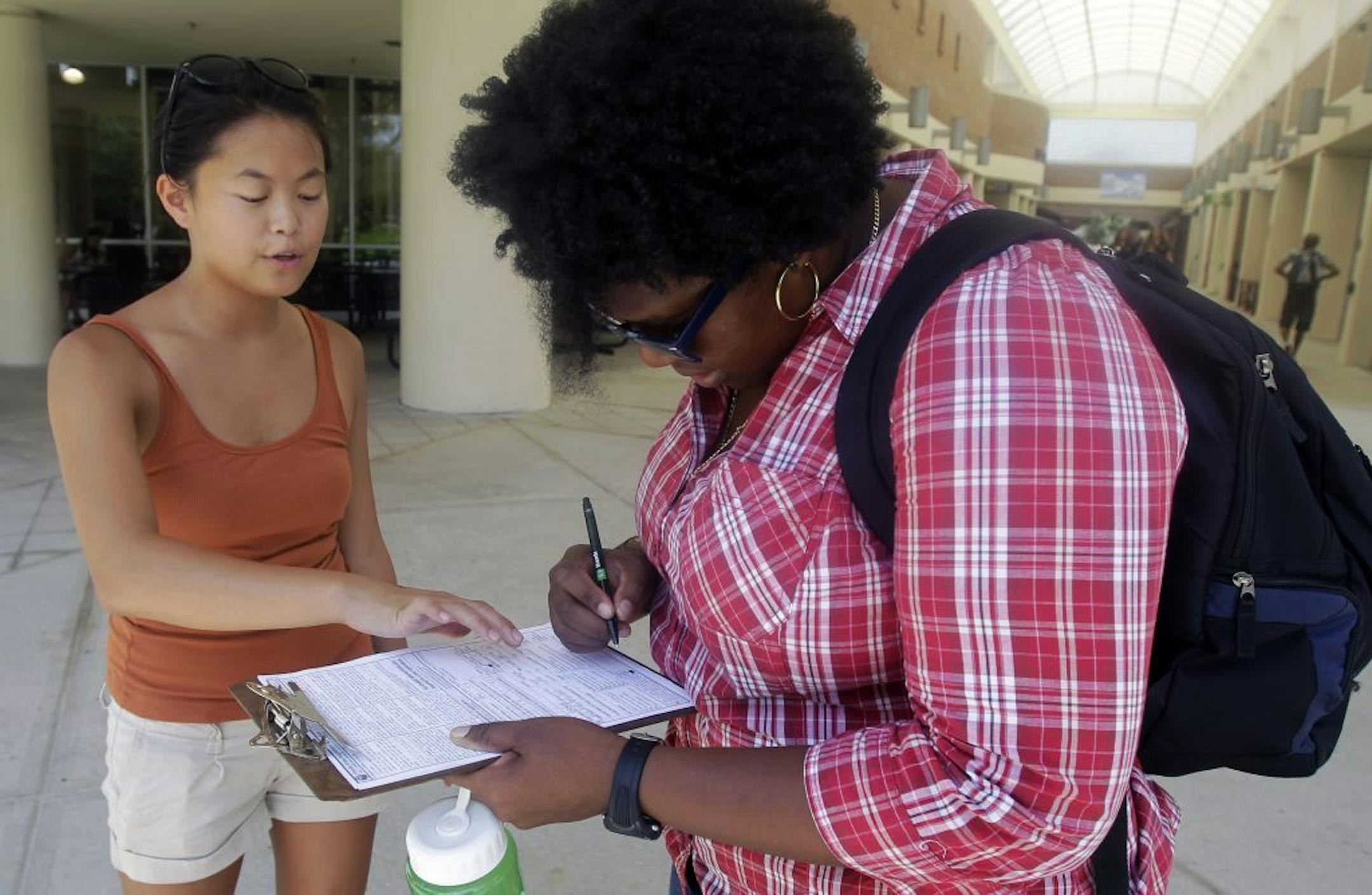 In this Tuesday, July 31, 2012, photo, Aubrey Marks, left, helps a University of Central Florida student to register to vote in Orlando, Fla.