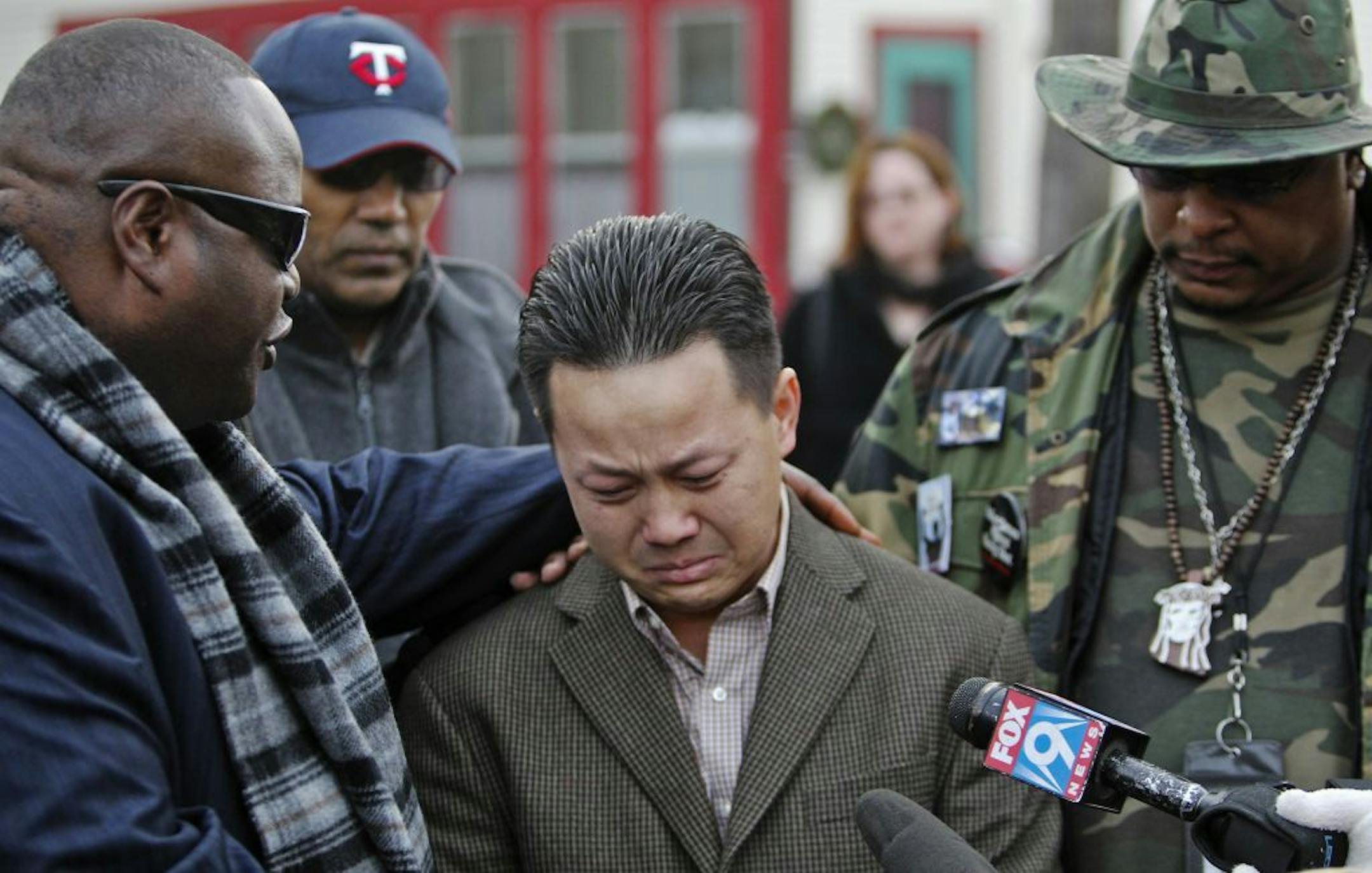 Dec. 8: Kia Xiong, the father of two-year old shooting victim Neegnco Xiong, is comforted by Rev. Harding Smith of the Spiritual Church of God, left, and peace activist K.G. Wilson, right.
