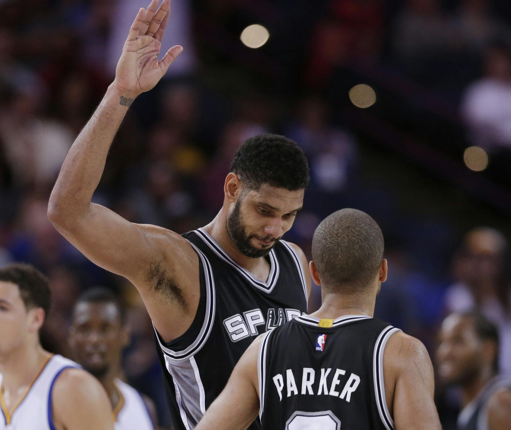 San Antonio Spurs' Tim Duncan, center, celebrates with teammate Tony Parker (9) in the closing minutes of the Spurs' 113-100 win over the Golden State Warriors in an NBA basketball game Tuesday, Nov. 11, 2014, in Oakland, Calif. (AP Photo/Marcio Jose Sanchez)