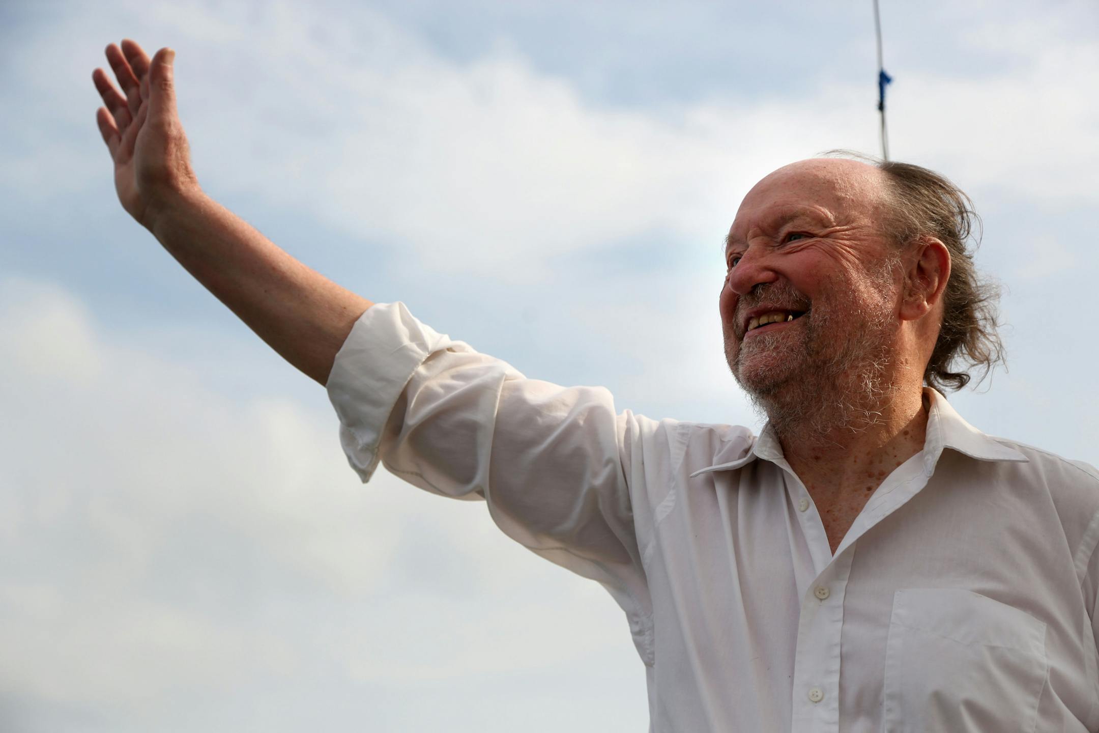 Werner Meybaum waved to passersby during a trip around Lake Calhoun. ] (KYNDELL HARKNESS/STAR TRIBUNE) kyndell.harkness@startribune.com Werner Meybaum, a retired computer engineer who offers "almost free" rides on his sailboat. The almost free part? Riders have to be willing to sing, and one of Meybaum's favorite songs is "Itsy Bitsy Spider." at Lake Calhoun in Minneapolis Min. Thursday, June 26, 2014.