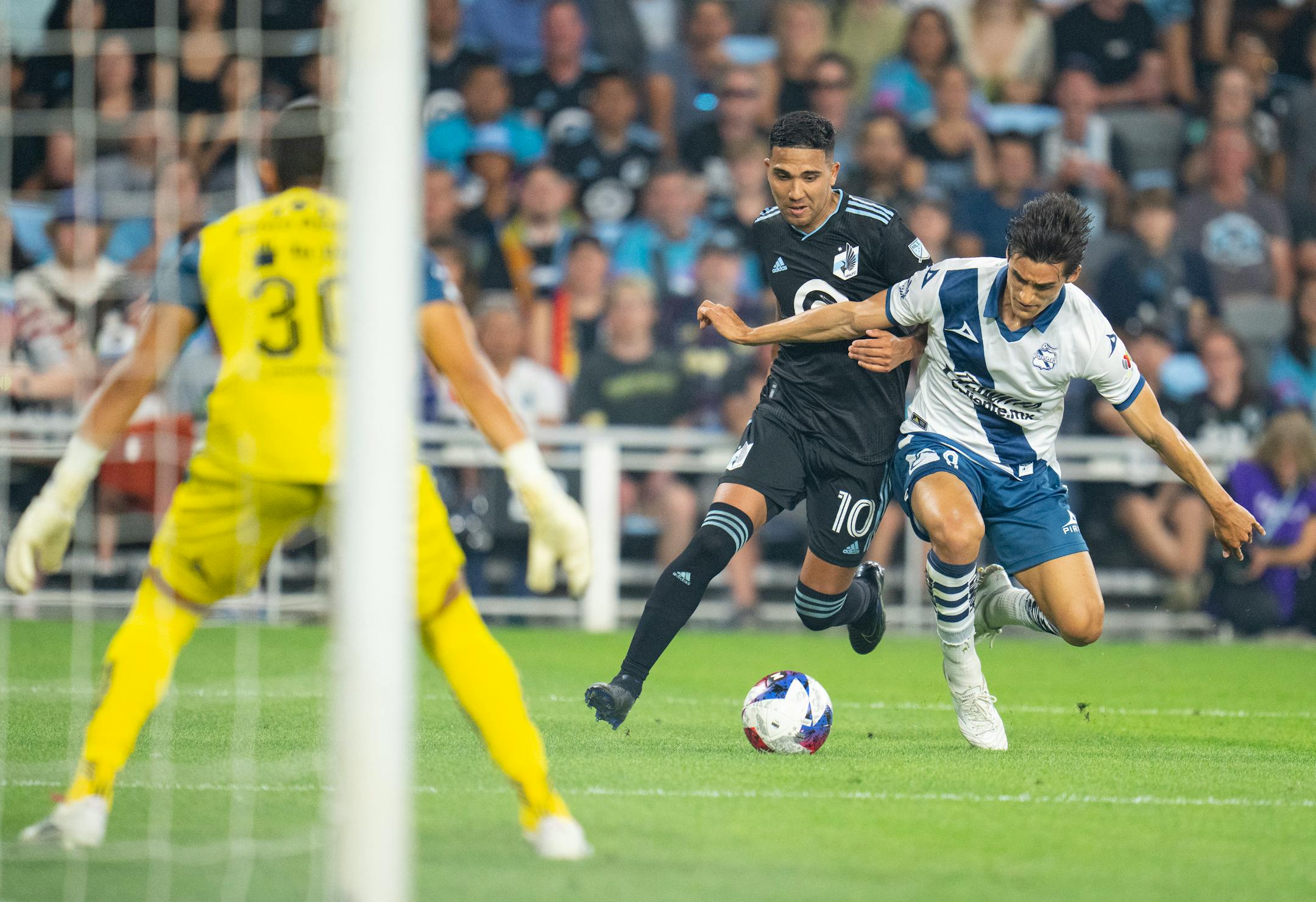 Minnesota United midfielder Emanuel Reynoso (10) fights with Puebla midfielder Fernando David Arce Juárez (8) for the ball near the net in the second half.