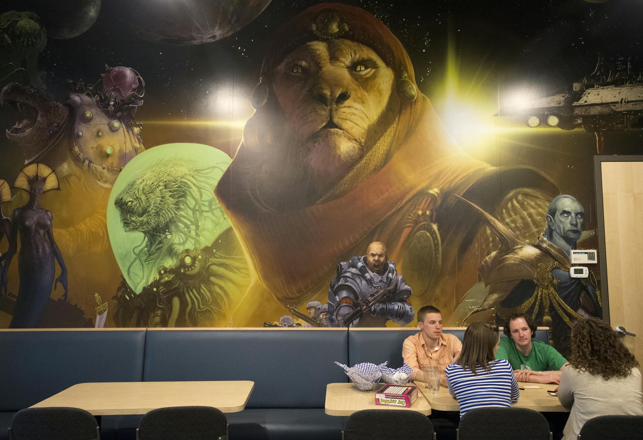 From left, Jordan and Andrea Nimlos and Johnny and Joanna Furst play the board game, "Say Anything," at Fantasy Flight gaming after grabbing a bite to eat at the cafe on Friday night. The group is sitting under artwork from the game "Twilight Imperium," one of Fantasy Flight's flagship games. ] (Aaron Lavinsky | StarTribune) aaron.lavinsky@startribune.com Gaming company "Fantasy Flight" has a cafe and bar where gamers can come eat, drink and game and has become a home for the after-hours gaming