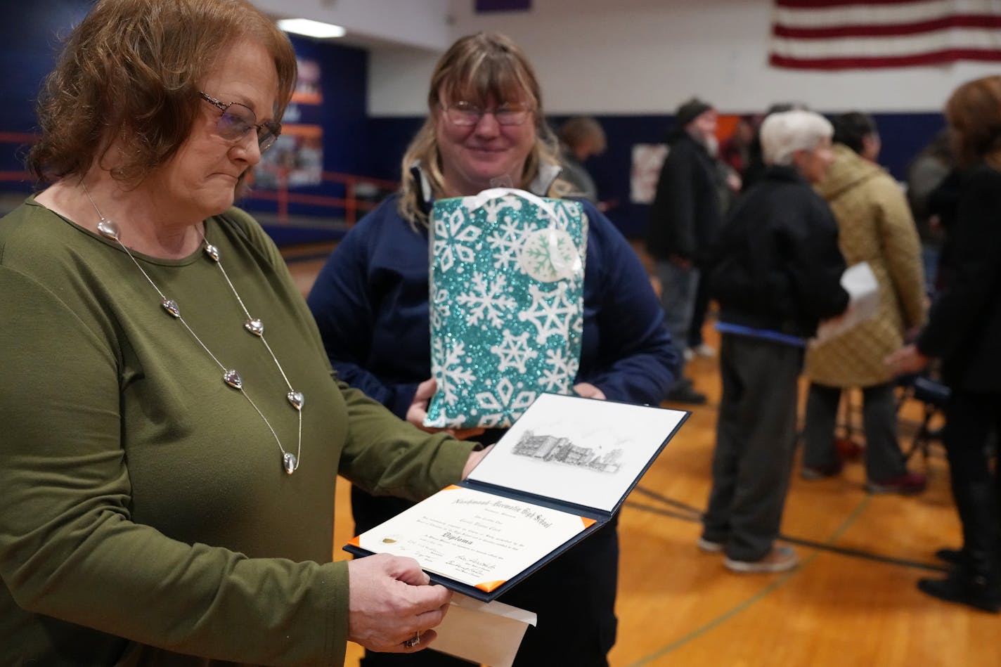 Bonnie McBride looks over a posthumous diploma for her mother Carole McBride, who in 1961 was denied a signed diploma because she wasn't able to meet the gym requirement due to her cerebral palsy, following a ceremony to honor her Tuesday, Dec. 12, 2023 at Nashwauk-Keewatin High School in Nashwauk, Minn. ] ANTHONY SOUFFLE • anthony.souffle@startribune.com