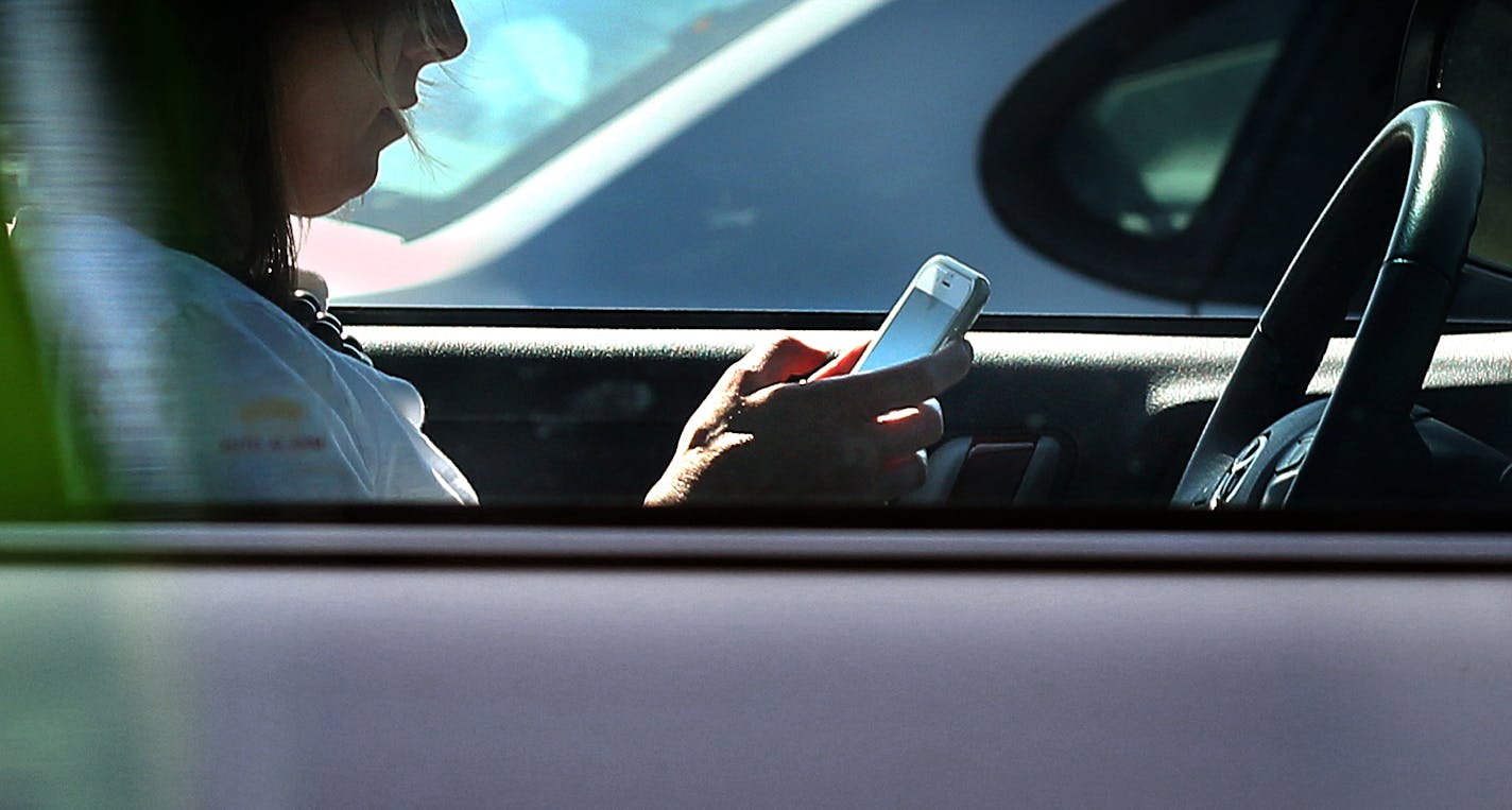 A driver texted on her cell phone while waiting for a traffic light to change in Eagan.