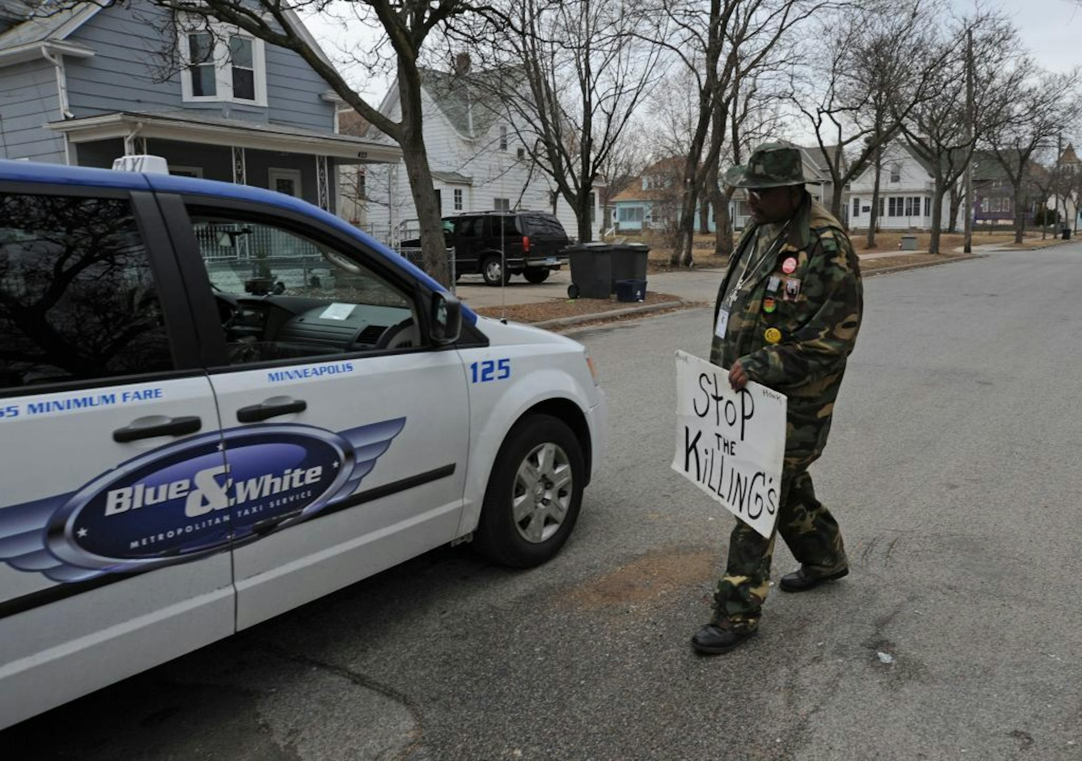 K.G. Wilson of Hope Ministries stood on 23rd Avenue N. in Minneapolis holding a sign while talking to a cabbie who was checking out the scene on Thursday. He was a few paces from where a cabdriver was shot Wednesday night and later died.