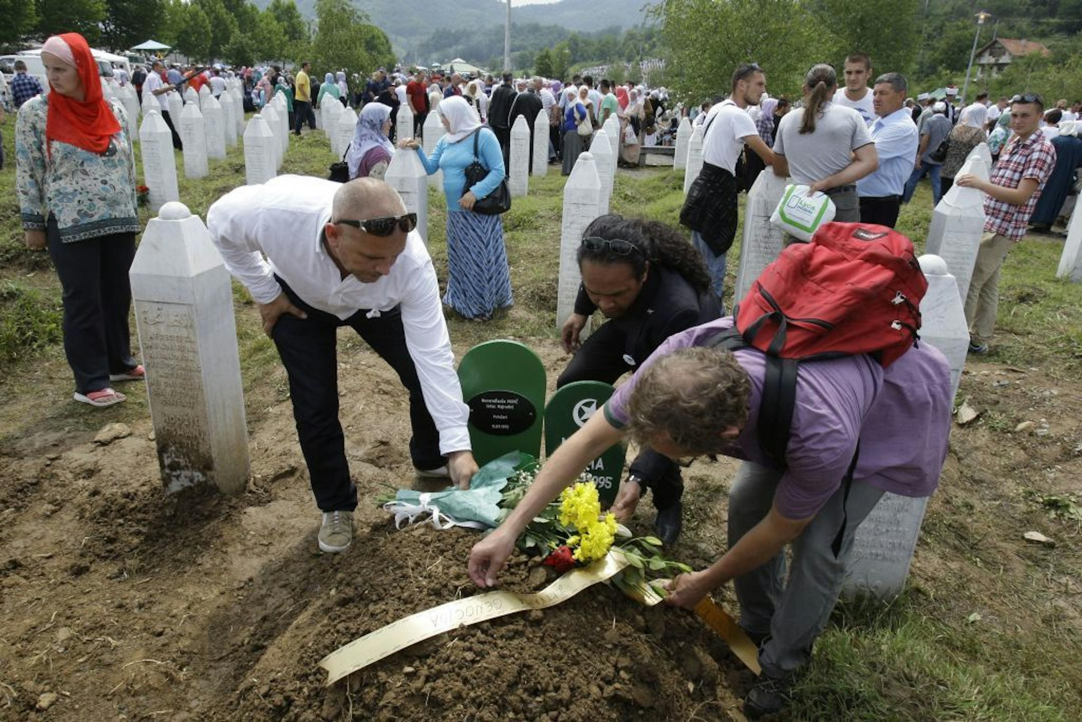 Dutch soldiers ex members of UN mission to Safe enclave of Srebrenica Adje Anakotta, center, Dion Vandenberg, right, Dave Maat, left, at the graveside of baby Muhic during a mass funeral for Srebrenica victims at the memorial center in Potocari, near Srebrenica, 160 kms east of Sarajevo, Bosnia, Thursday, July 11, 2013. Mother, Hava Muhic, believes she should be baking a cake, with her husband calling friends and family for a party, instead, Muhic stood Thursday above the smallest pit in the cem
