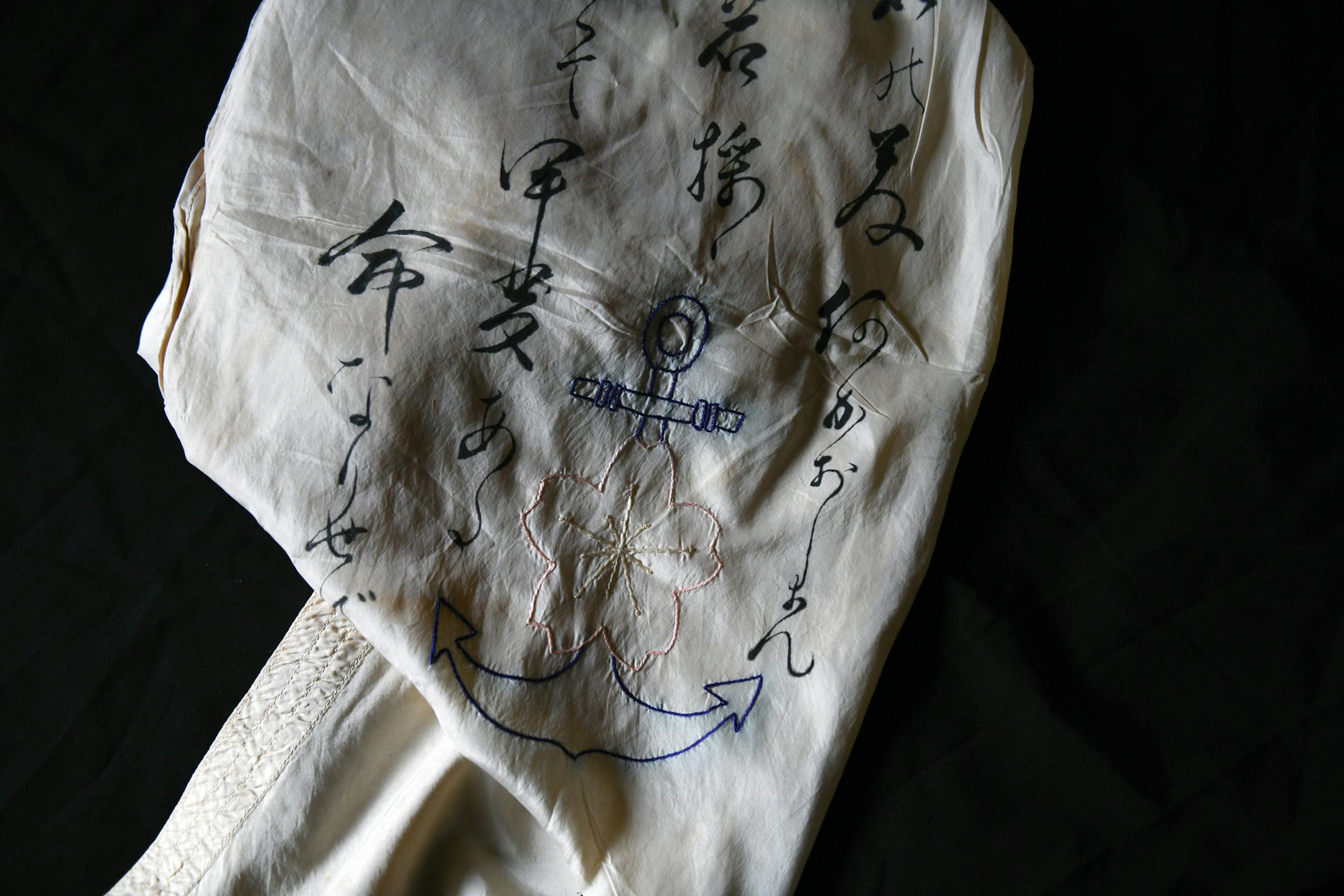 A silk scarf worn by Kazuo Odachi on missions during World War II is displayed at his home in Tokyo on Sep. 7, 2020. It is made of parachute cloth and embroidered with cherry blossoms and a blue anchor, the symbol of his unit.
