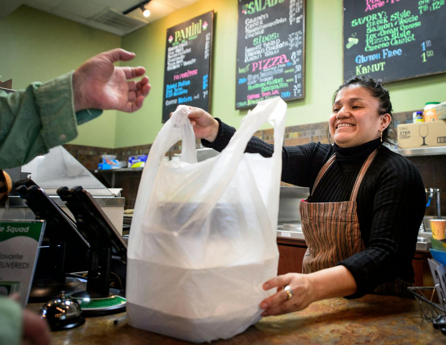 Sandra Mejia handed a takeout order to a customer at Vitali&#x2019;s Bistro in St. Louis Park. The restaurant uses biodegradable plastic bags but could switch to paper or reusable bags if the city becomes the first in the state to ban plastic bags altogether.