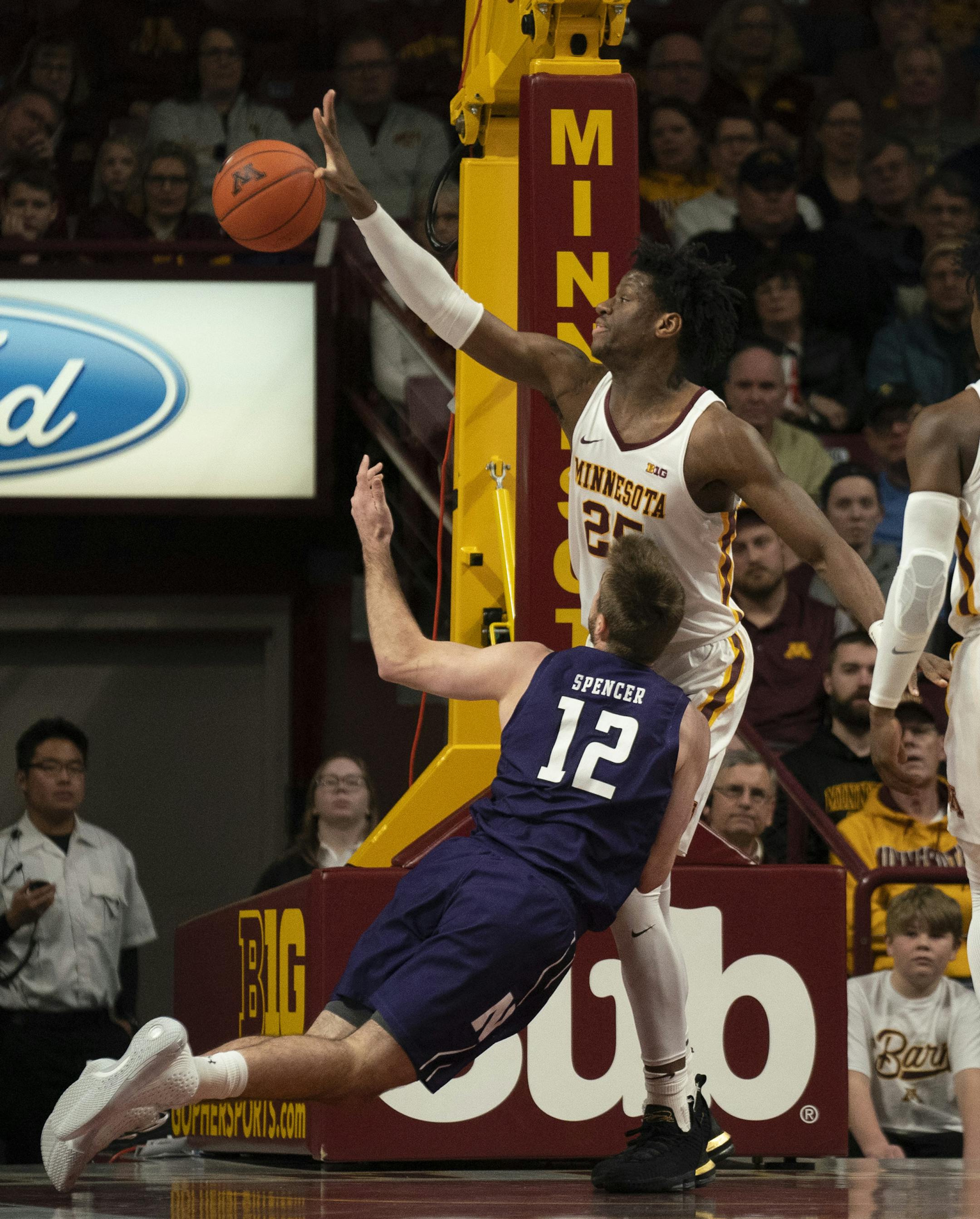 Northwestern Wildcats guard Pat Spencer (12) lost his footing as he drove to the hoop and into Minnesota Golden Gophers center Daniel Oturu (25) in the first half. ] JEFF WHEELER • Jeff.Wheeler@startribune.com The University of Minnesota men's basketball team faced Northwestern in an NCAA basketball game Sunday night, January 5, 2020 at Williams Arena in Minneapolis.