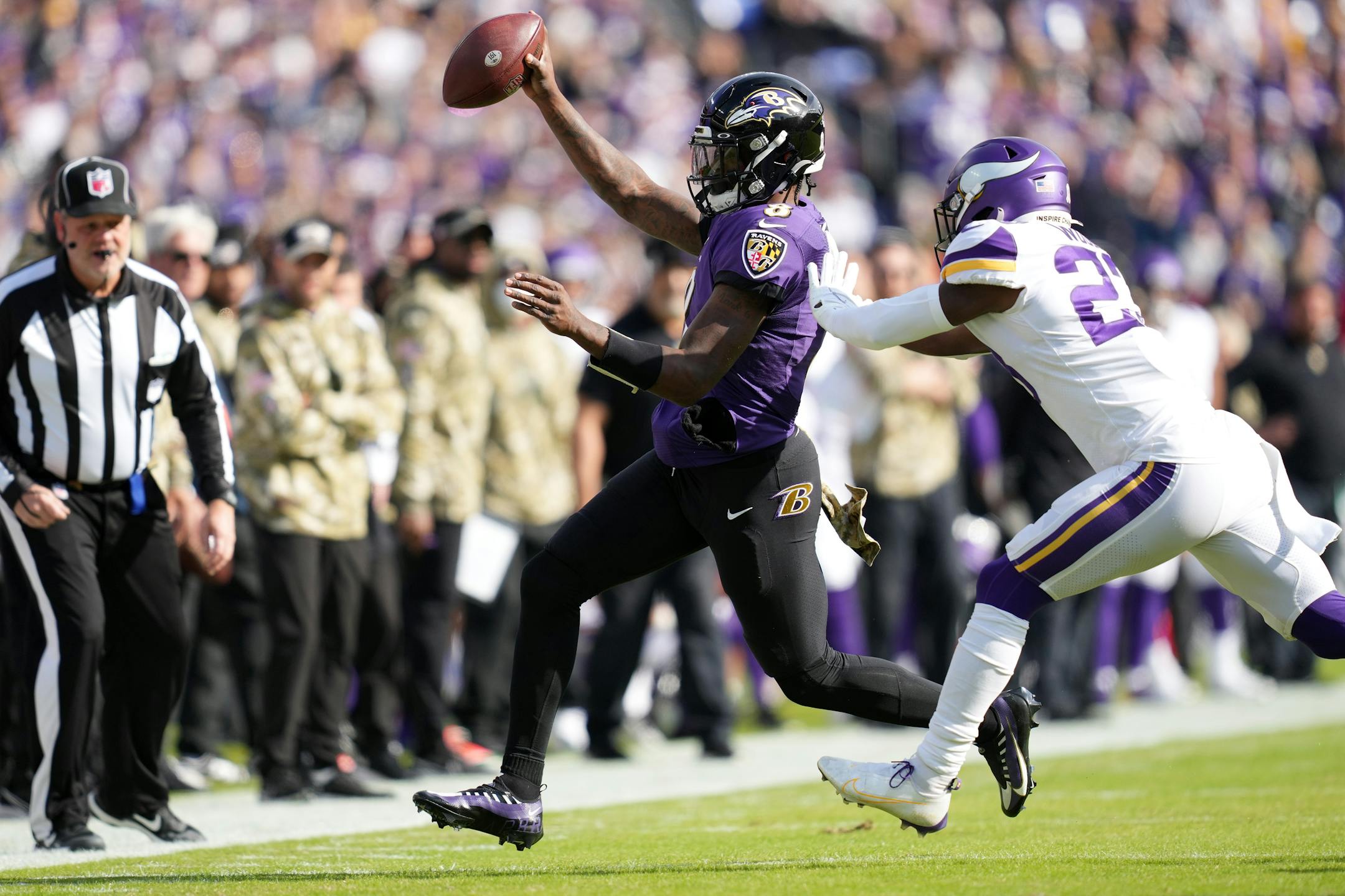 Ravens quarterback Lamar Jackson (8) got the first down as scrambled out of bounds away from Vikings free safety Xavier Woods (23) while running the ball in the first quarter of an NFL game between the Minnesota Vikings and the Baltimore Ravens Sunday, Nov. 7, 2021 at M&T Bank Stadium in Baltimore.