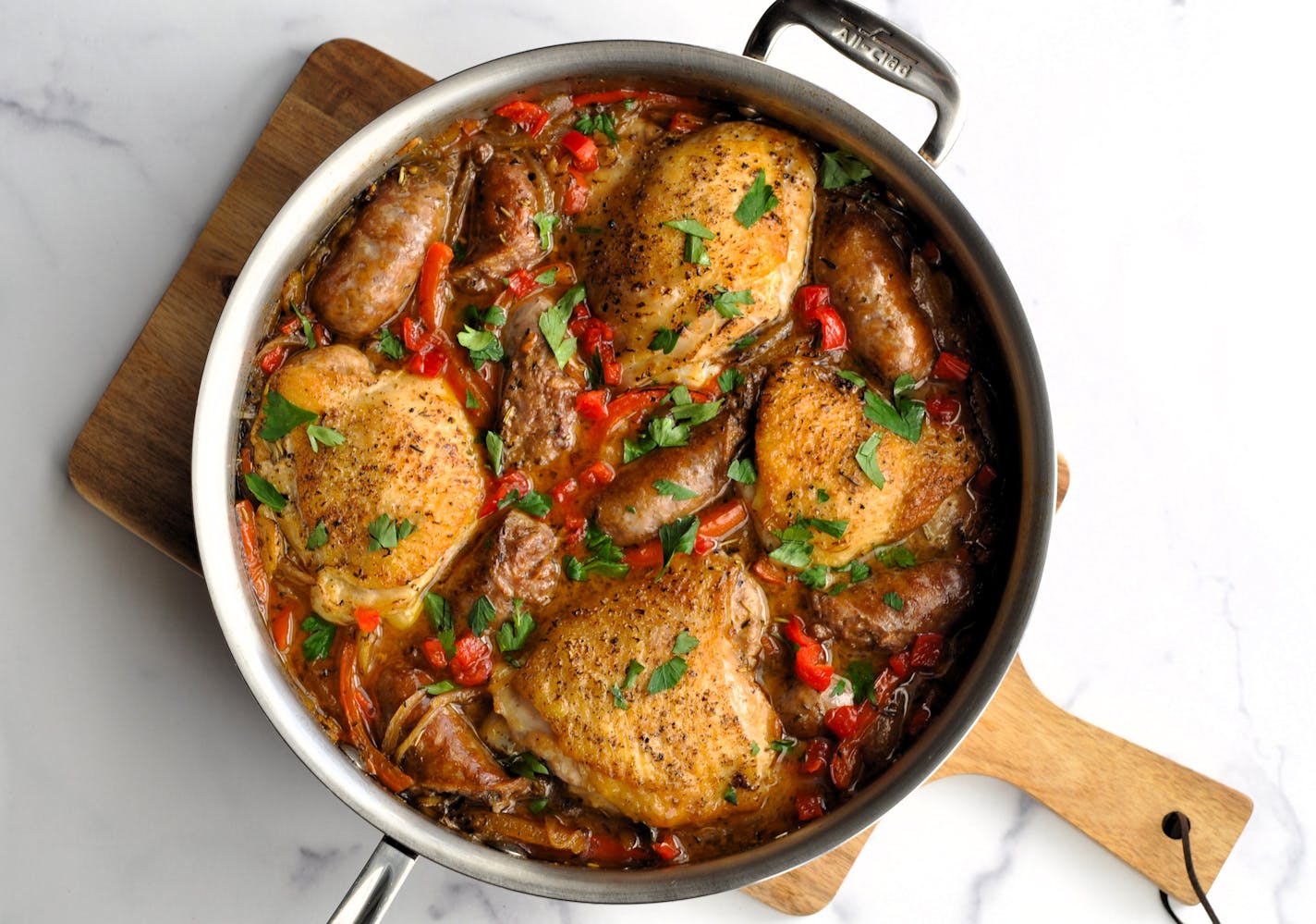 A pan of Chicken Scarpariello with vegetables on top.