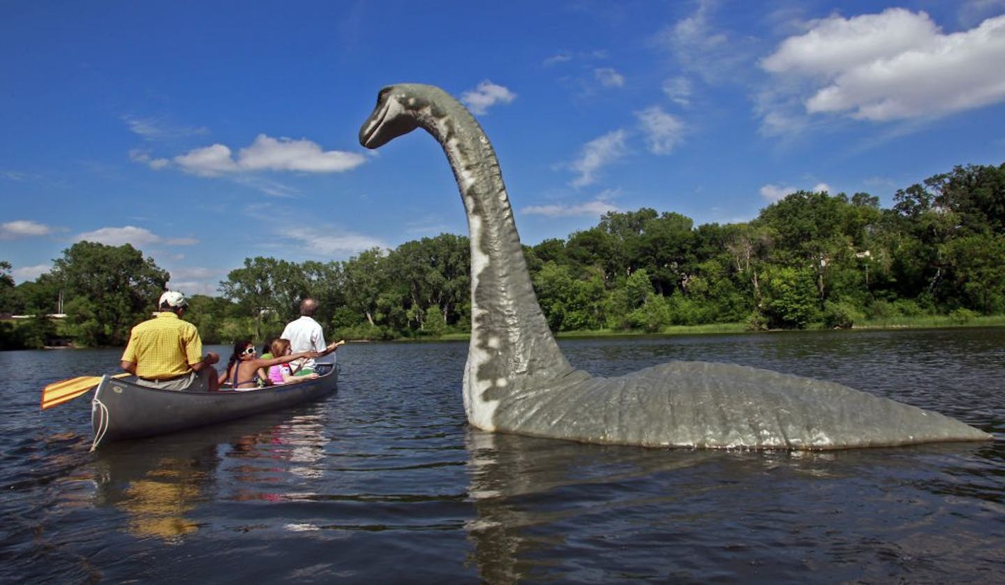 A family paddles in for a close look at "Minne," the lake creature that will be anchored at Brownie Lake until mid-July.