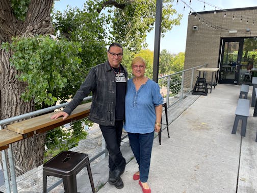 Sean Sherman and Lidia Bastianich at Owamni on the patio during the filming of Changemakers. Both are smiling to the camera.