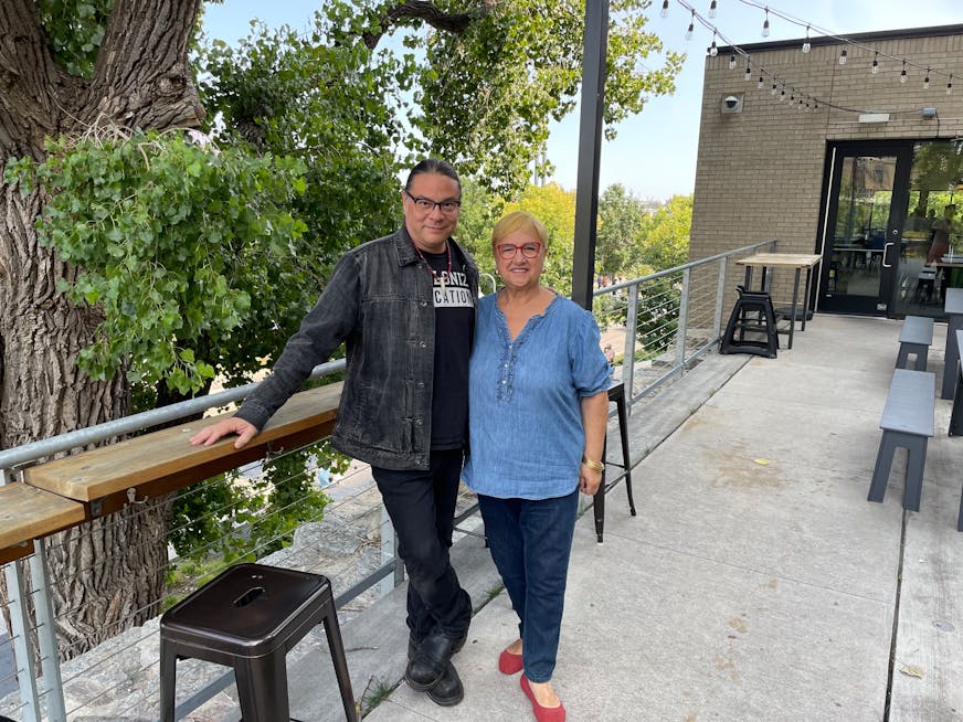 Sean Sherman and Lidia Bastianich at Owamni on the patio during the filming of Changemakers. Both are smiling to the camera.