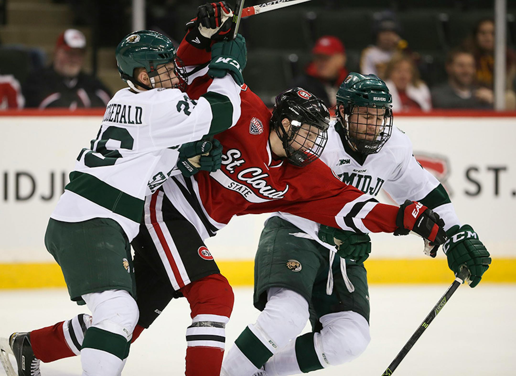 Beavers forward Myles Fitzgerald (26) and defenseman Dan Billett (2) tried to keep Huskies forward Patrick Newell (14) off the puck in the second period Sunday afternoon.