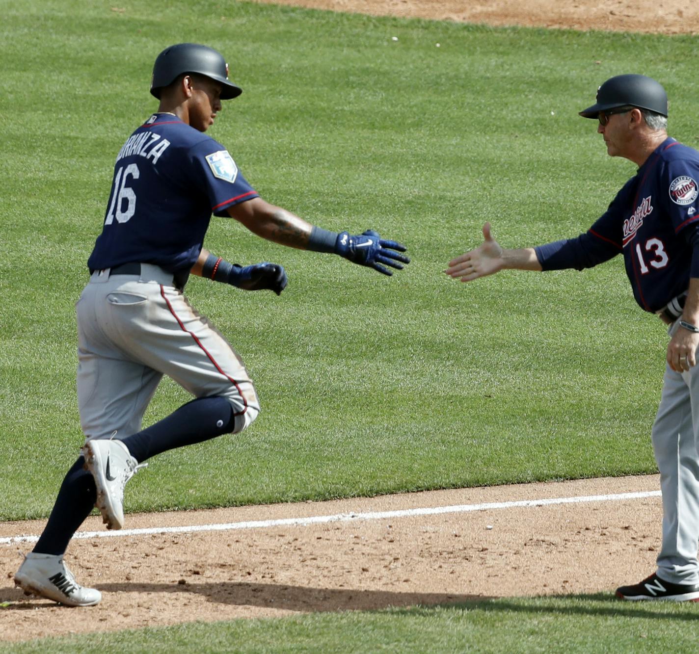 Minnesota Twins' Ehire Adrianza (16) is congratulated by third base coach Gene Glynn (13) after hitting a two-run home run during the fifth inning of an exhibition spring training baseball game against the St. Louis Cardinals, Thursday, March 1, 2018, in Jupiter, Fla. (AP Photo/Jeff Roberson)