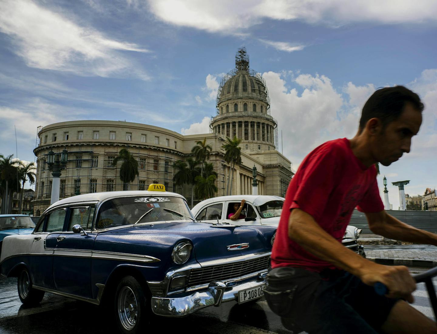 FILE - In this July 15, 2016 file photo, a man cycles alongside taxi drivers near the Capitol building in Havana, Cuba. A rare poll of Cuban public opinion taken in late 2016 has found that most Cubans approve of normal relations with the United States and large majorities want more tourism and private business ownership. (AP Photo/Ramon Espinosa, File) ORG XMIT: MIN2017042814300321