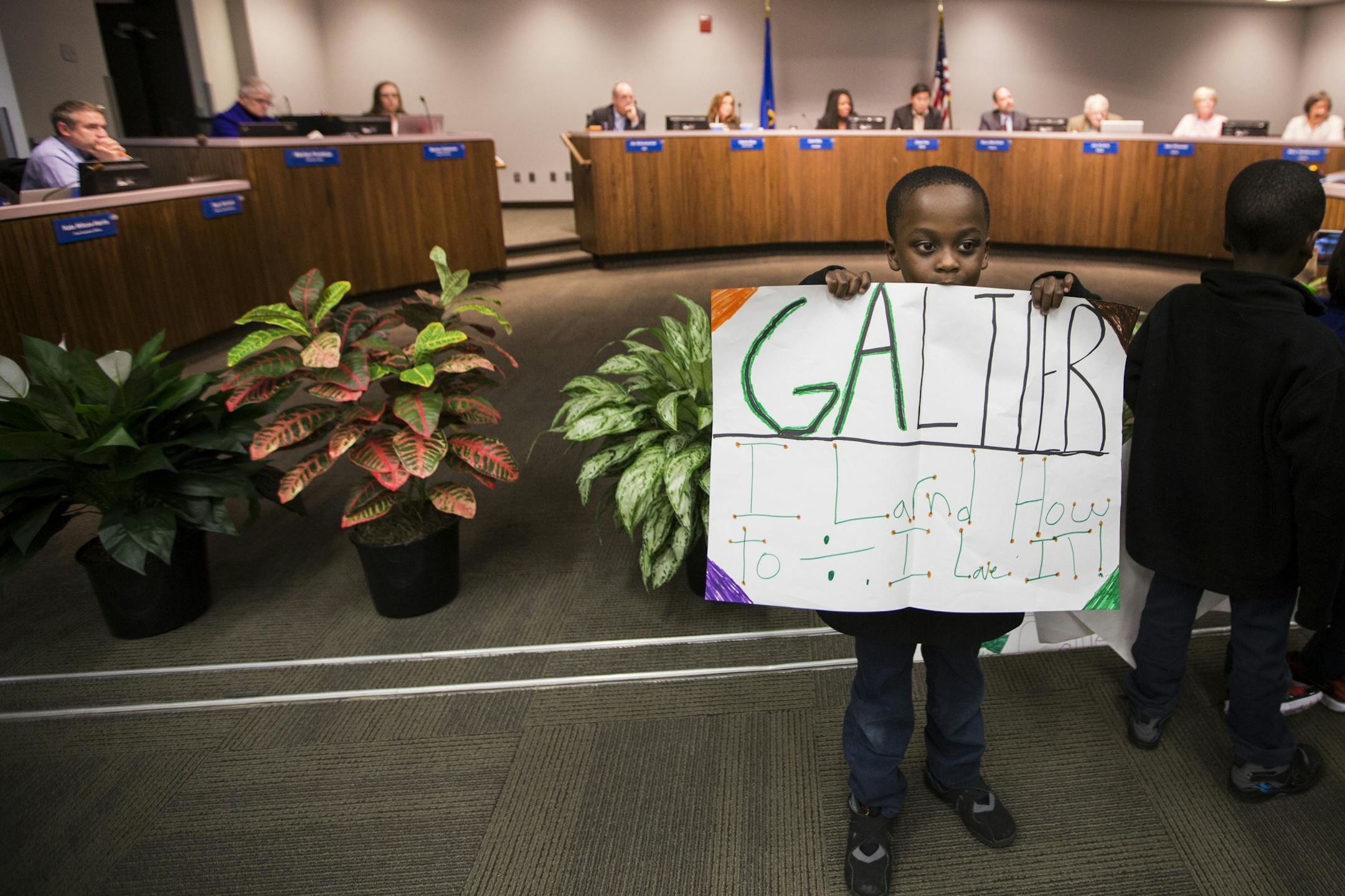 A kindergartener at Galtier Community School holds a sign during the public comment portion of a St. Paul School Board meeting.