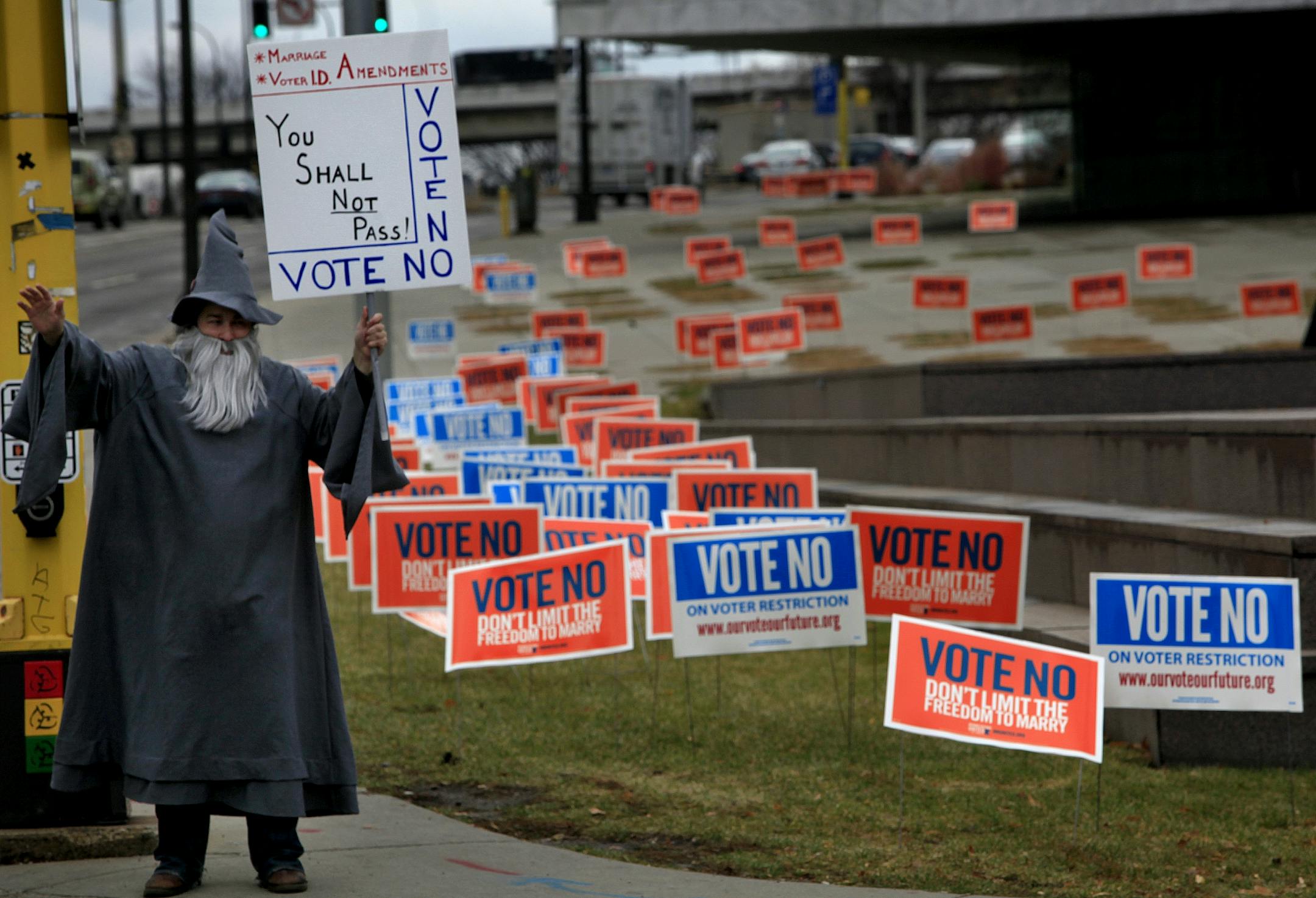 Adam Sharp waived to cars as they honked their horns and gave him the thumbs up as he held his sign to vote no for the marriage and voter I.D. Amendments. Adam Sharp dressed up in costume and took the day off to make people aware of the Vote No amendments. Adam said," A vote yes for the marriage amendment is hurtful to fellow americans and would treat some people like second class citizens. I have friends that are gay and this is just not right nor is it fair." Adam Sharp stood on the corner of