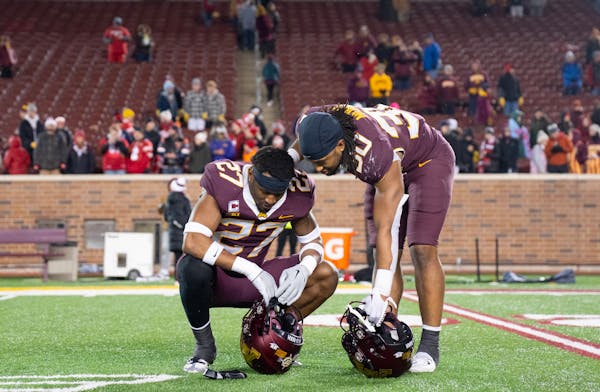 Gophers defensive back Tyler Nubin (27) is comforted by brother Jordan Nubin (30) after losing to Wisconsin 28-14 on Saturday