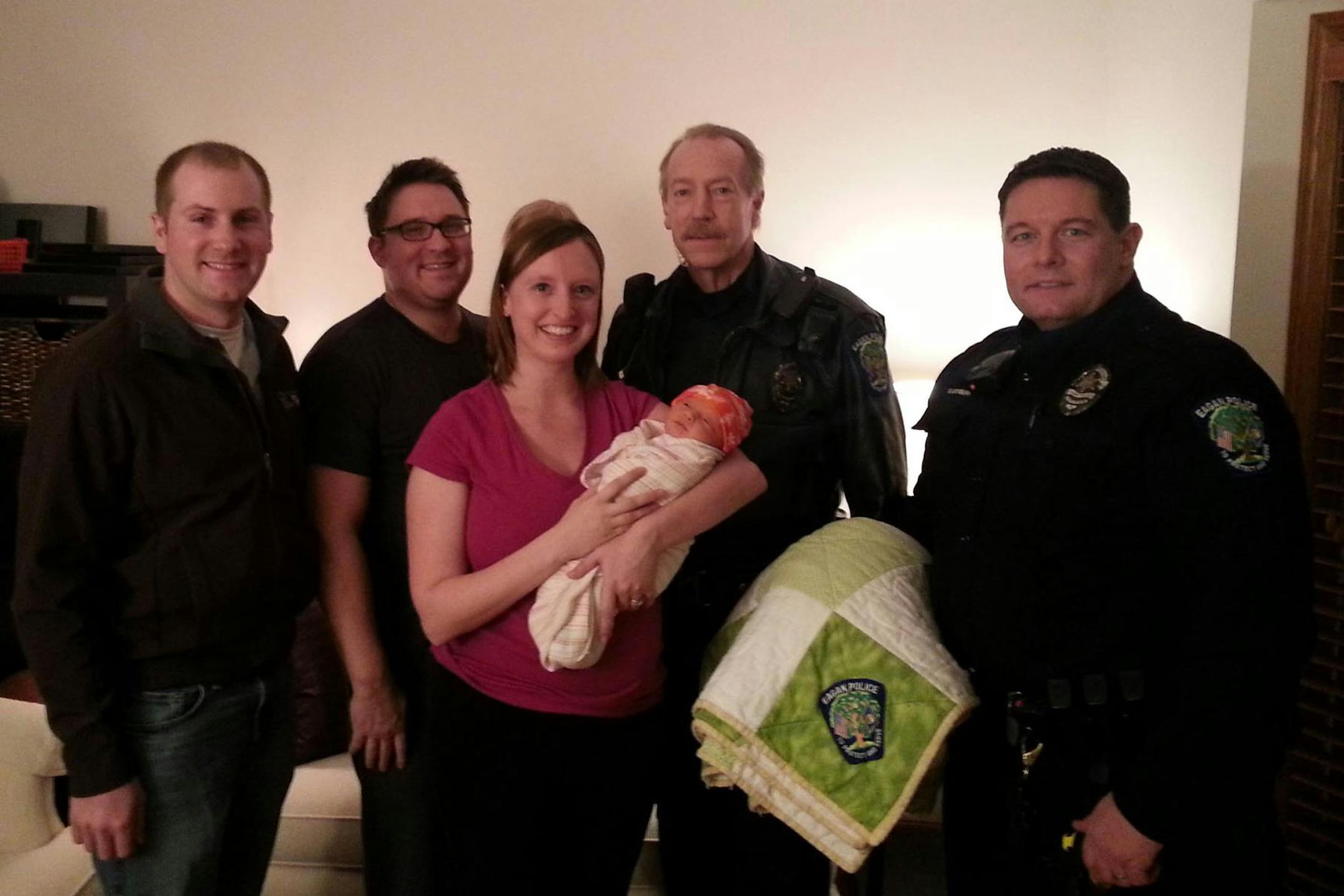 Well after the dramatic at-home birth mom Angela Reinders and daughter Maggie gathered with (from left) dispatcher Matt Ausmus, dad Michael Reinders and Eagan police officers Tom Nelson and Steve Lounsbury at the parents' home Monday. The blanket was a gift from police to the family. Courtesy Eagan Police Department