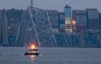 A container ship rests against wreckage of the Francis Scott Key Bridge near sunrise on Wednesday, March 27, 2024, in Baltimore, Md.  Recovery efforts