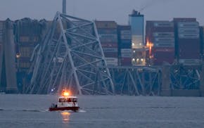 A container ship rests against wreckage of the Francis Scott Key Bridge near sunrise on Wednesday, March 27, 2024, in Baltimore, Md.  Recovery efforts