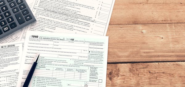 top view of forms for usa taxes with a pen and an electronic calculator, empty spaces for custom text at the right (3d render). istock