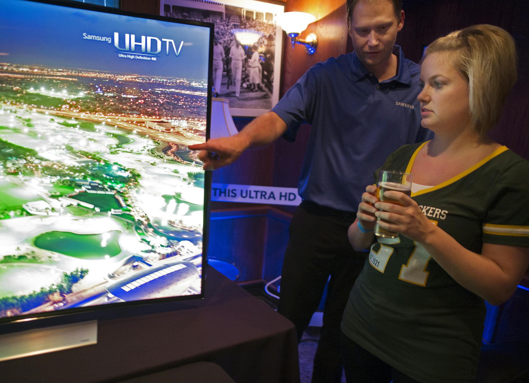 Kraig Levang of Samsung showed Molly Trudeau of Plymouth the merit of a curved 4K television. Trudeau, a big Packers fan said her boyfriend was working in order to help pay for the 4k set they planned to buy this weekend.] On October 2, 2014 at Britt's Pub,This fall, Best Buy is taking its sales pitch directly to sports fans hanging out in bars. The idea is to show them in person the difference in 4K TVs while watching a big game. While Best Buy knows they are still too expensive to be a big hol