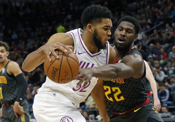 Atlanta Hawks' Alex Poythress, right, tries to reach the ball as Minnesota Timberwolves' Karl-Anthony Towns drives during the first half of an NBA bas