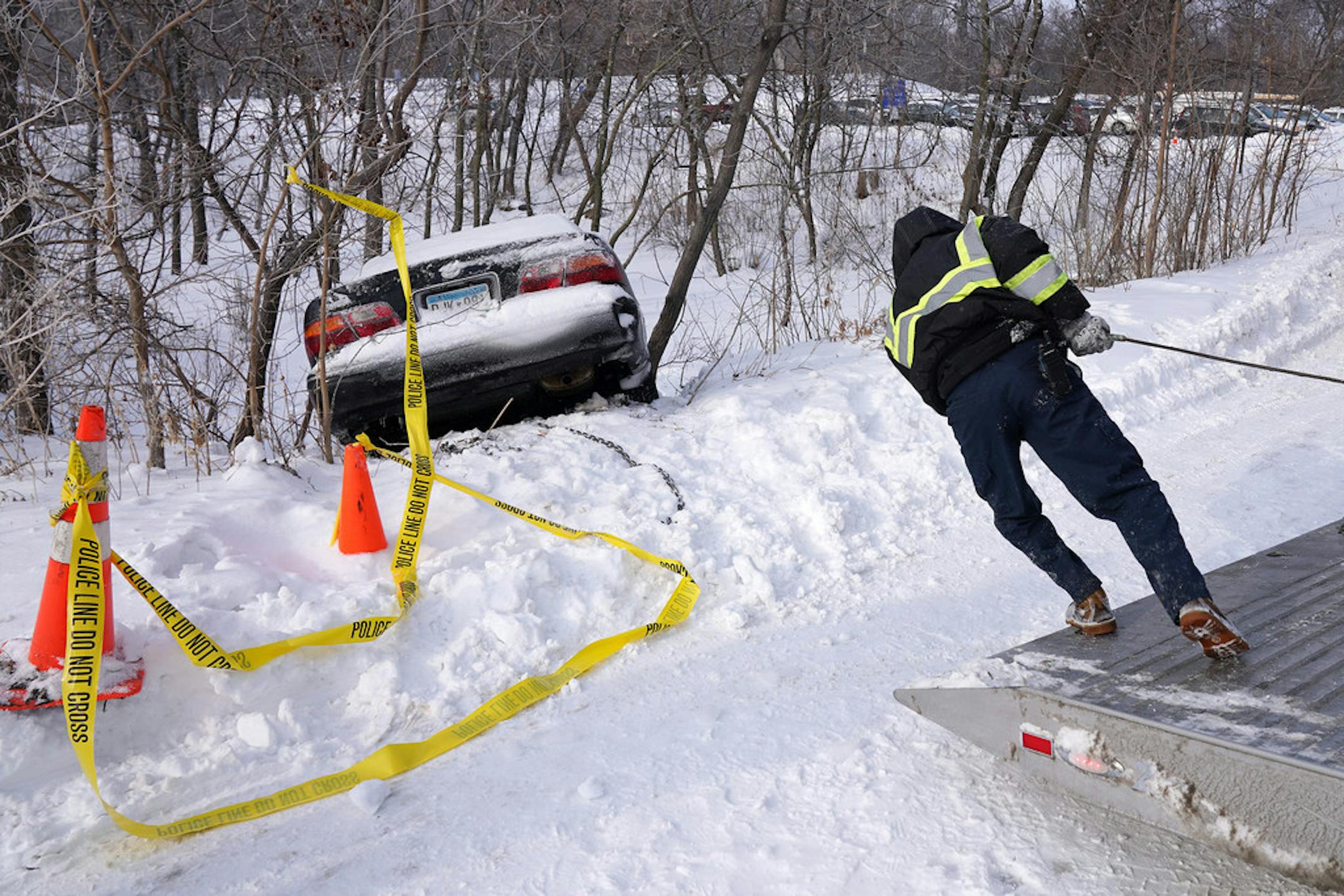 Jason Arce, a driver with Galeana's Towing, worked to pull Tyler Freed's car from a ditch Saturday morning after it skidded off the road Friday night near the Lake Harriet Bandshell.