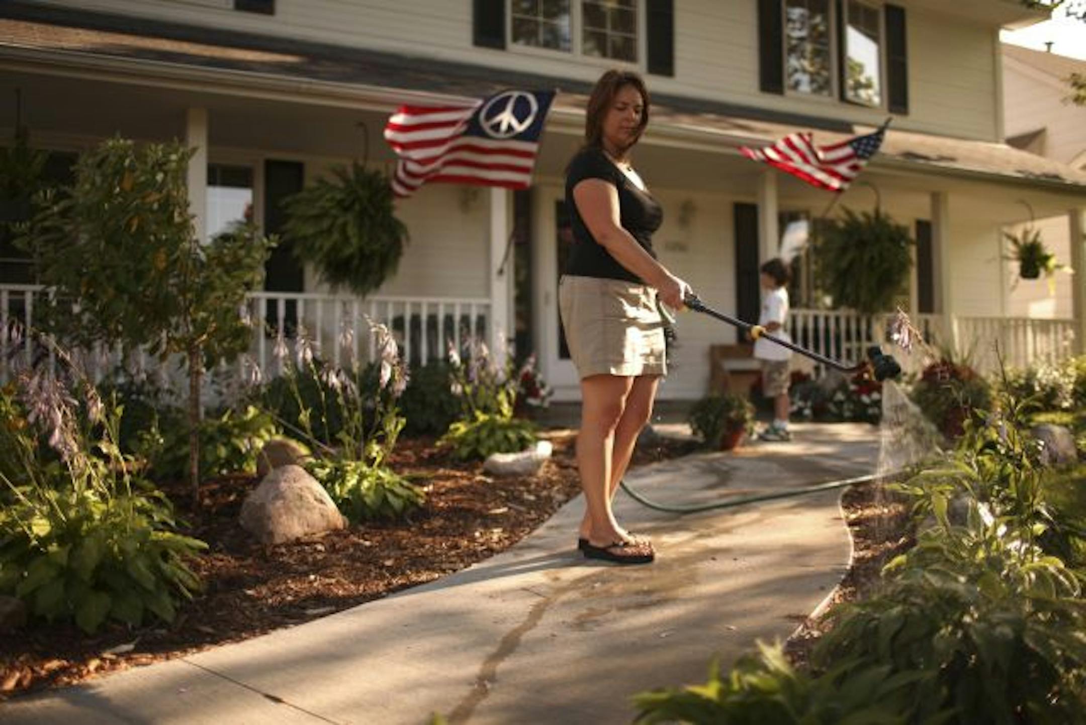 Stacey Allen's son, Cabot, kept her company while she watered the flower beds in front of her family's home on Rivervew Rd. in Eden Prairie Friday evening.