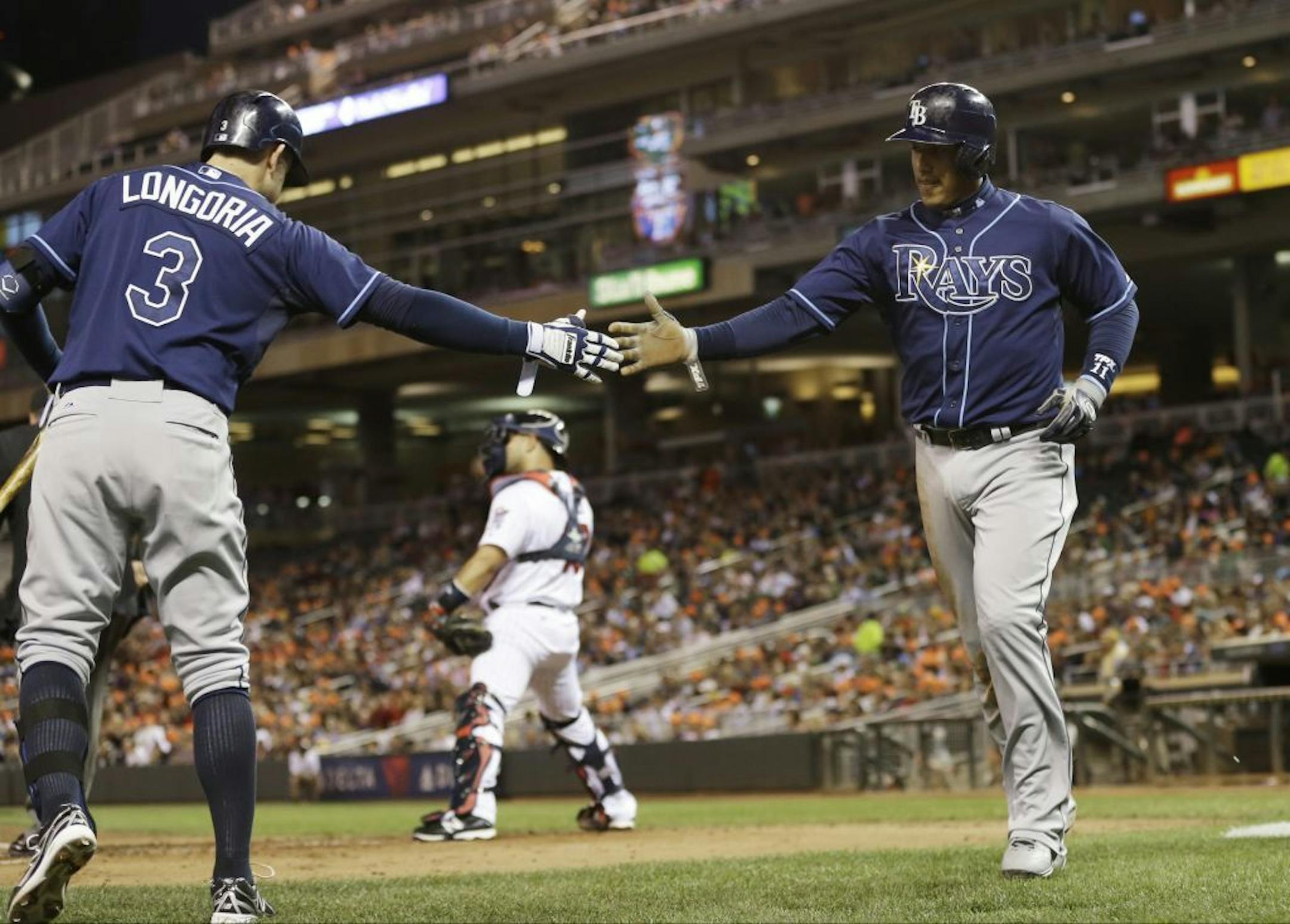 Tampa Bay Rays' Yunel Escobar is greeted by Evan Longoria, left, after he scored from third on a single by James Loney off Minnesota Twins pitcher Kevin Correia in the third inning of a baseball game, Friday, Sept. 13, 2013 in Minneapolis.