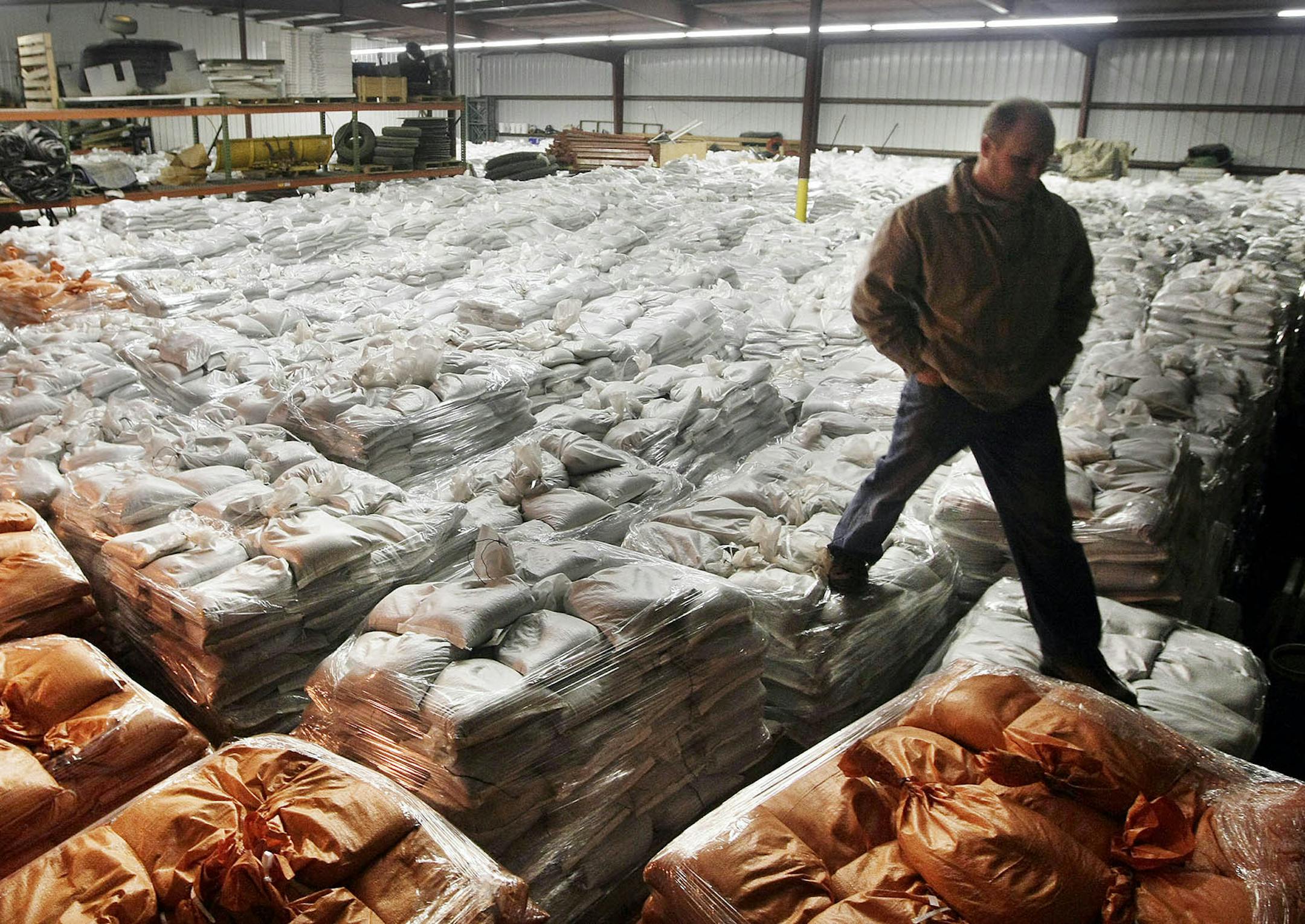 In a March 22, 2011 photo, Fargo Public Works Services Manager Mark Williams walks over the mountain of sandbags kept in the storage facilities, north of the Fargo Public Works building. The city is keeping its stock of 3 million sandbags in heated buildings to keep them from freezing before they can be deployed to fight a major flood. (AP Photo/The Forum, David Samson) ORG XMIT: MIN2014061315331317