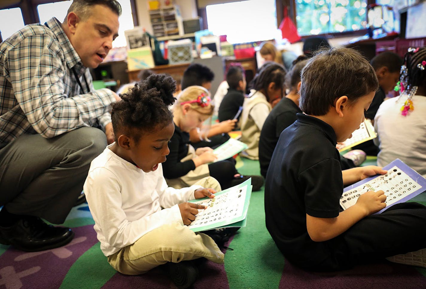 Kindergarten teacher David Boucher watched a student read her letters at Folwell Performing Arts Magnet School in Minneapolis.