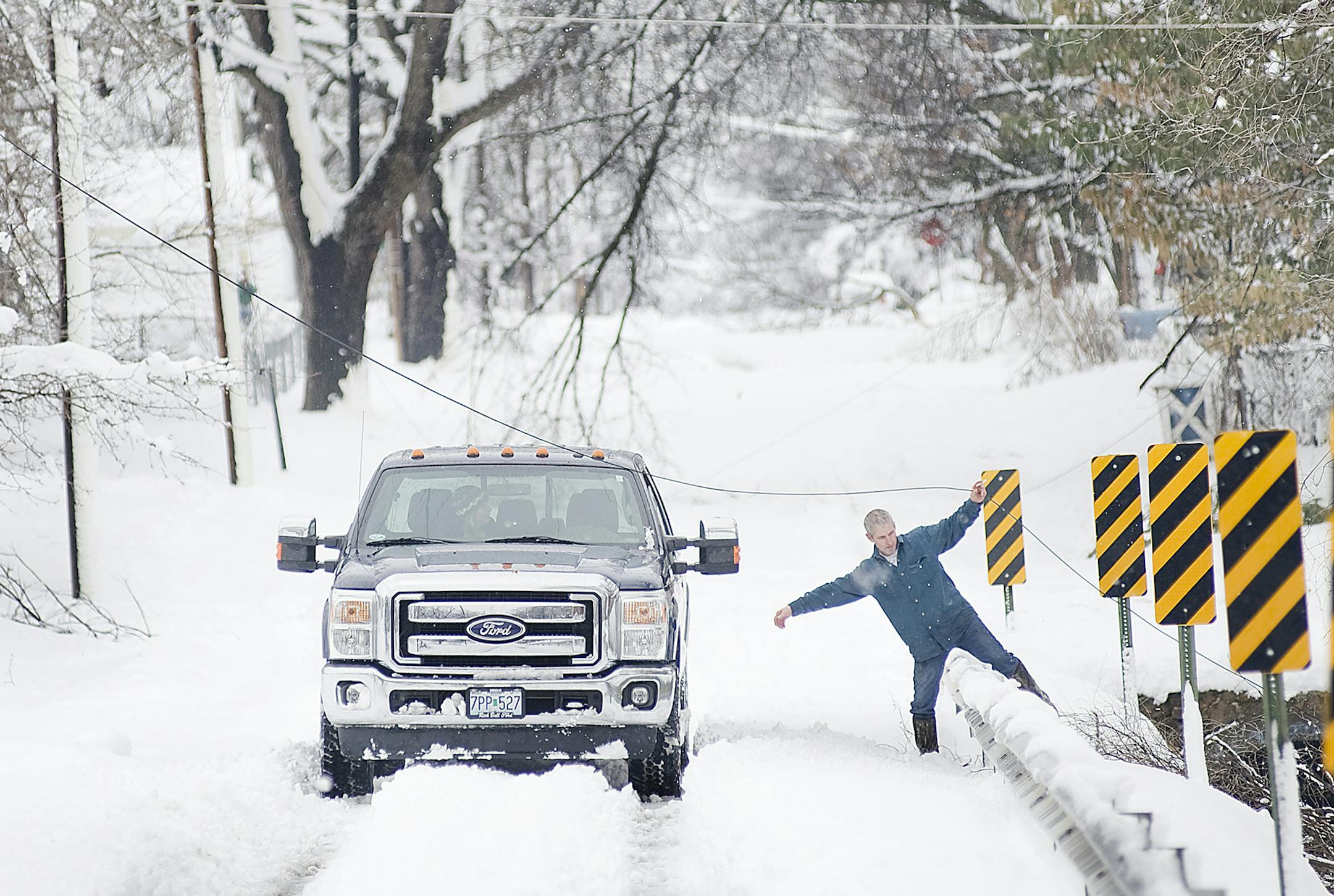 Tedd Hendrix, of Sedalia, Mo., frees a line of cable from downed branches Tuesday, Feb. 26, 2013, as he works to tie the line off so that it is elevated and out of the road. A snow storm, the second in less than a week, dumped about a foot of snow in Sedalia, knocking out power around the town and collapsing the roofs of several buildings. (AP Photo/Sedalia Democrat, Sydney Brink)