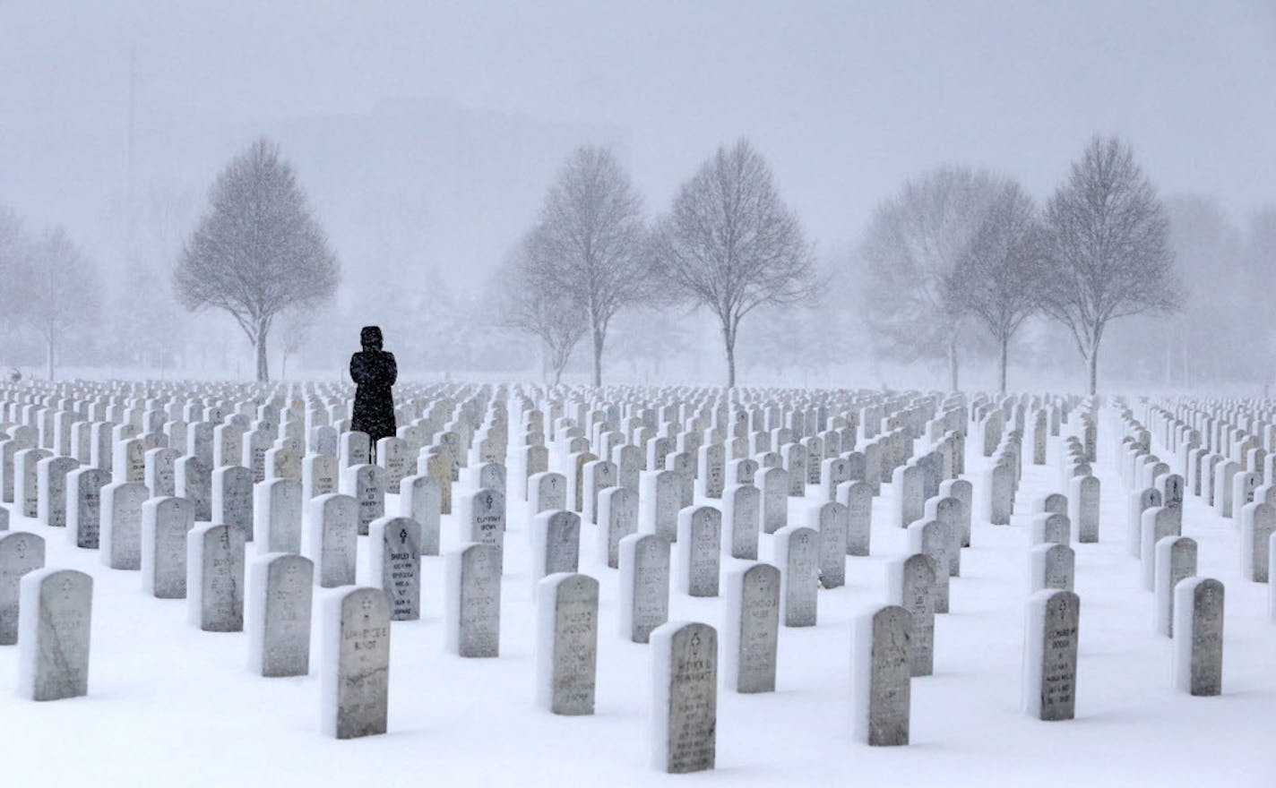 A woman visits a gravesite in the Fort Snelling National Cemetery in a snowstorm in March 2016.