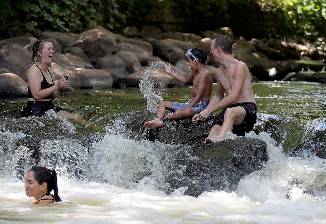 People cool off in Minnehaha Creek in Minneapolis on a hot day in July 2020.