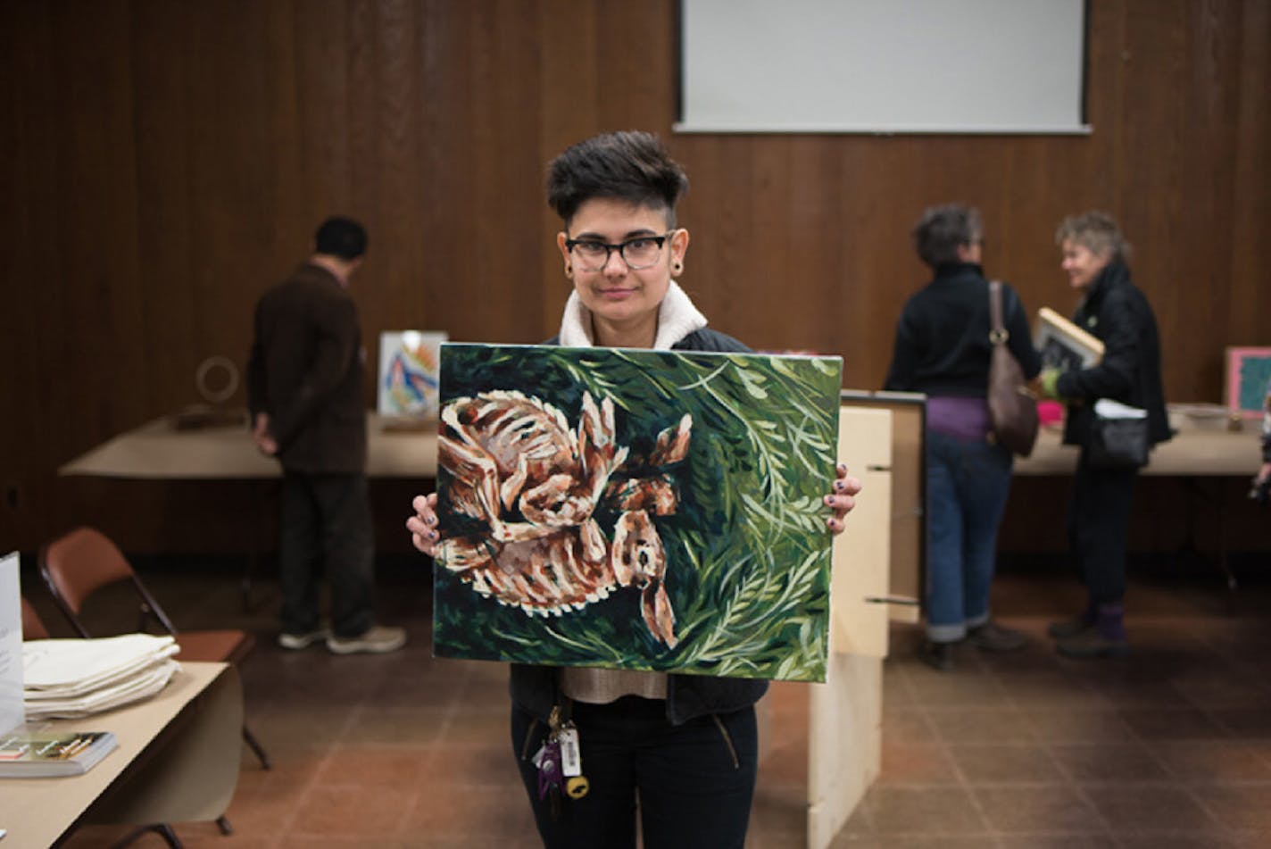 Paige Coletti-Swenson holds "Nest," by Carley McHenry, at a past Minneapolis Art Lending Library event.