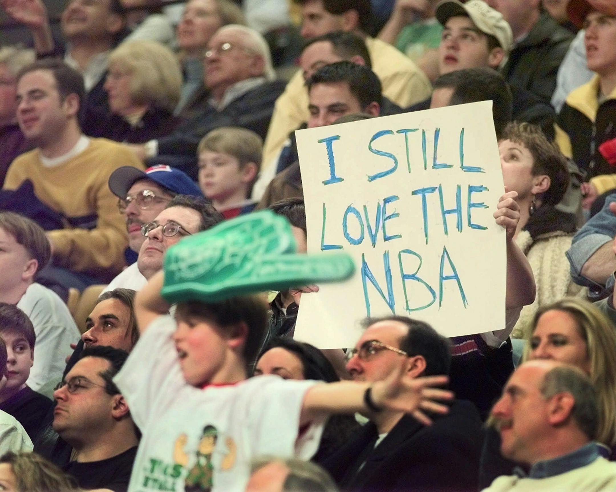 A fan holds up a sign in the seats at the Fleet Center during a break in the action between the Boston Celtics and the Toronto Raptors during the NBA season opener in Boston Friday night, Feb. 5, 1999. (AP Photo/Elise Amendola)