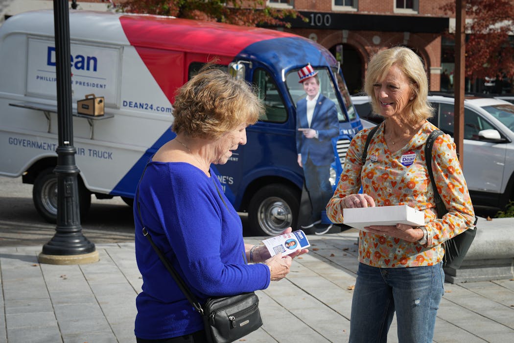 Dean Phillips volunteer Sarah Eigenmann, right, handed out Phillips’ literature outside the New Hampshire State House inviting people to a Friday rally.