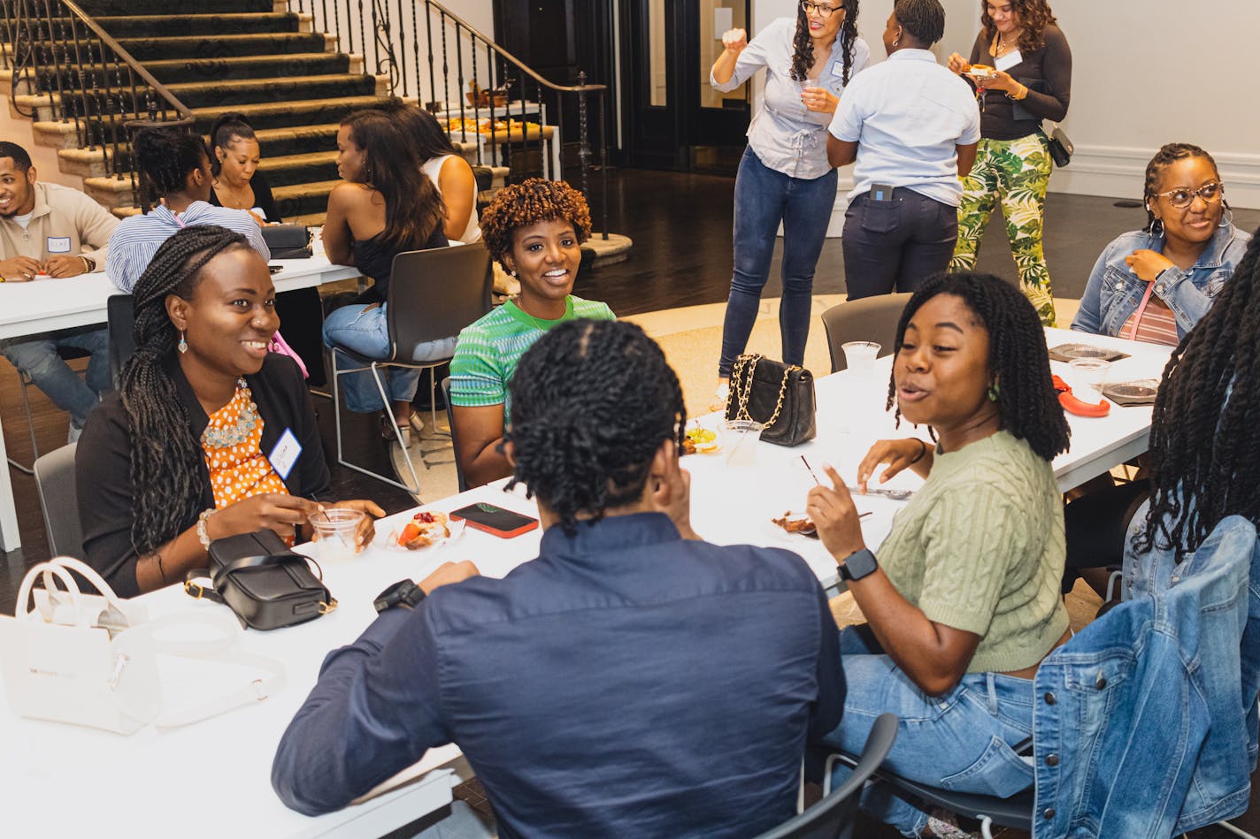 A half-dozen young Black professionals smiled and conversed at a table while others milled about in a retail/office space.