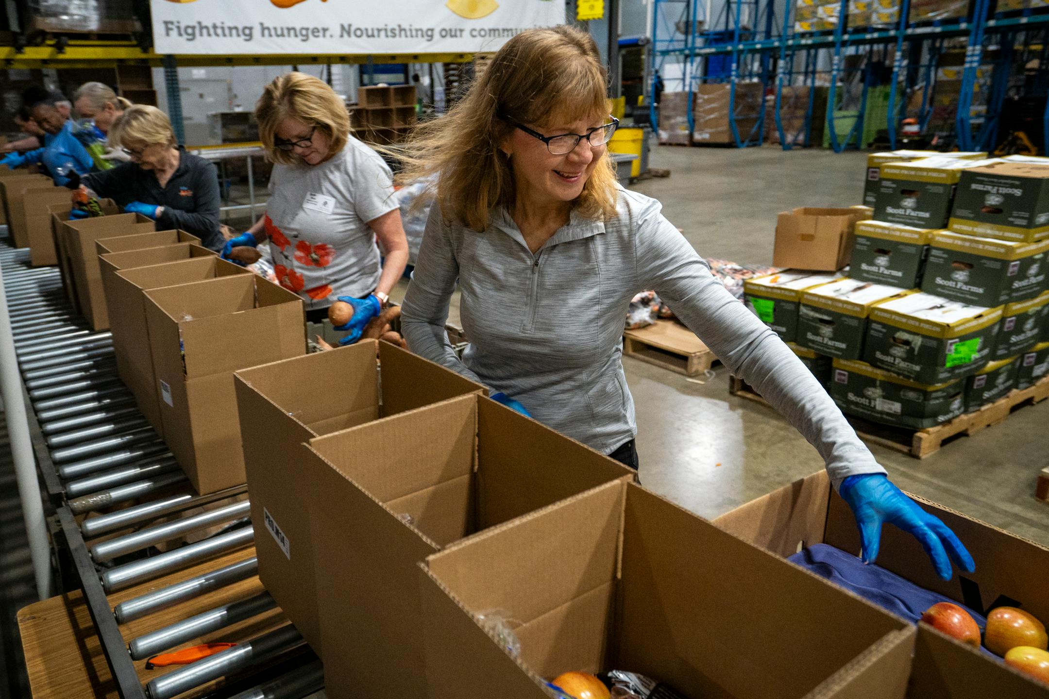 Lisa Merry, a volunteer with the Food Group, helps pack apples into produce boxes.