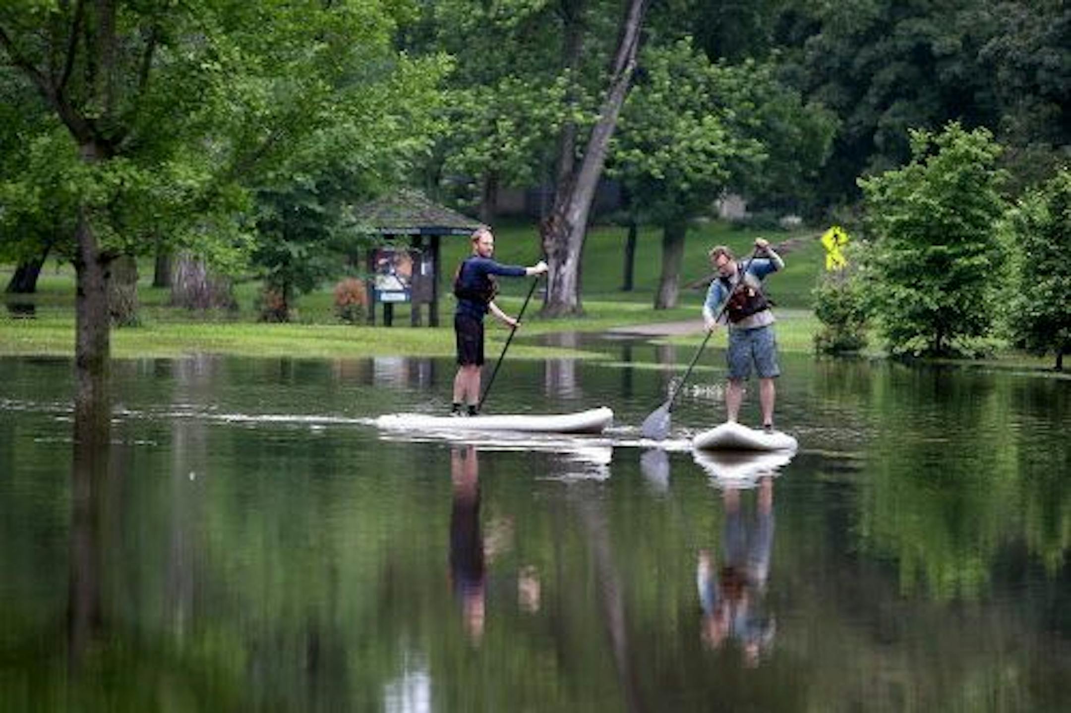 A new way to commute to work? Ryan Welty, left, and JB Matthews made their way across flooded Minnehaha Parkway on stand-up paddle boards, Friday, June 20, in Minneapolis.