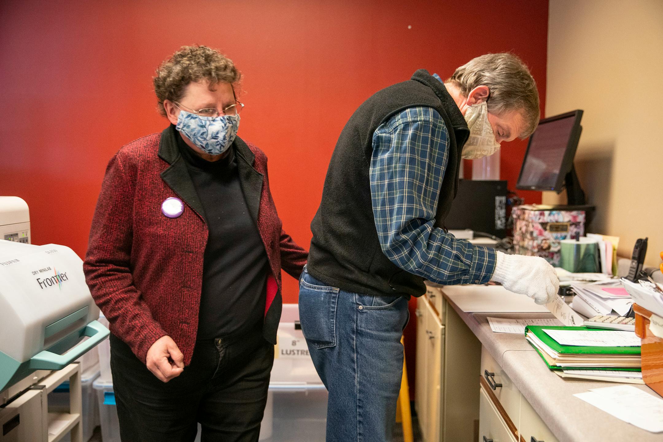 (Left) Cathy and Mike Mennes, co-owners of First Photo, worked on finishing the last photo print orders that the store would ever take on Wednesday, March 31, 2021.