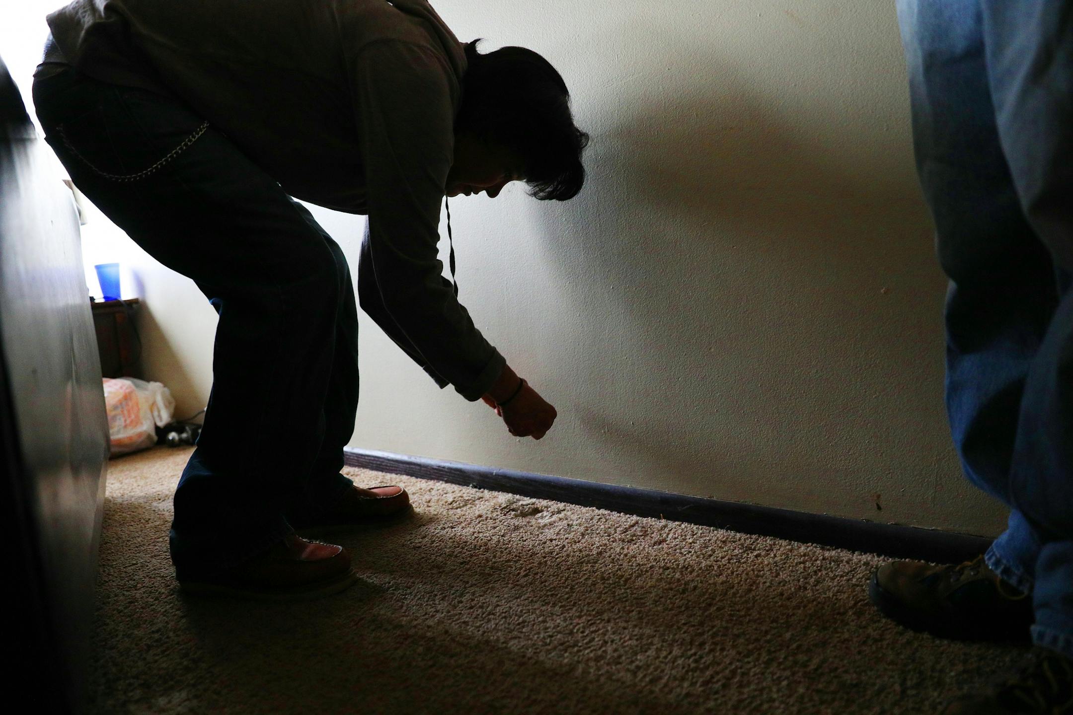 Bridget Peake points out bugs crawling along the baseboard of her apartment unit.