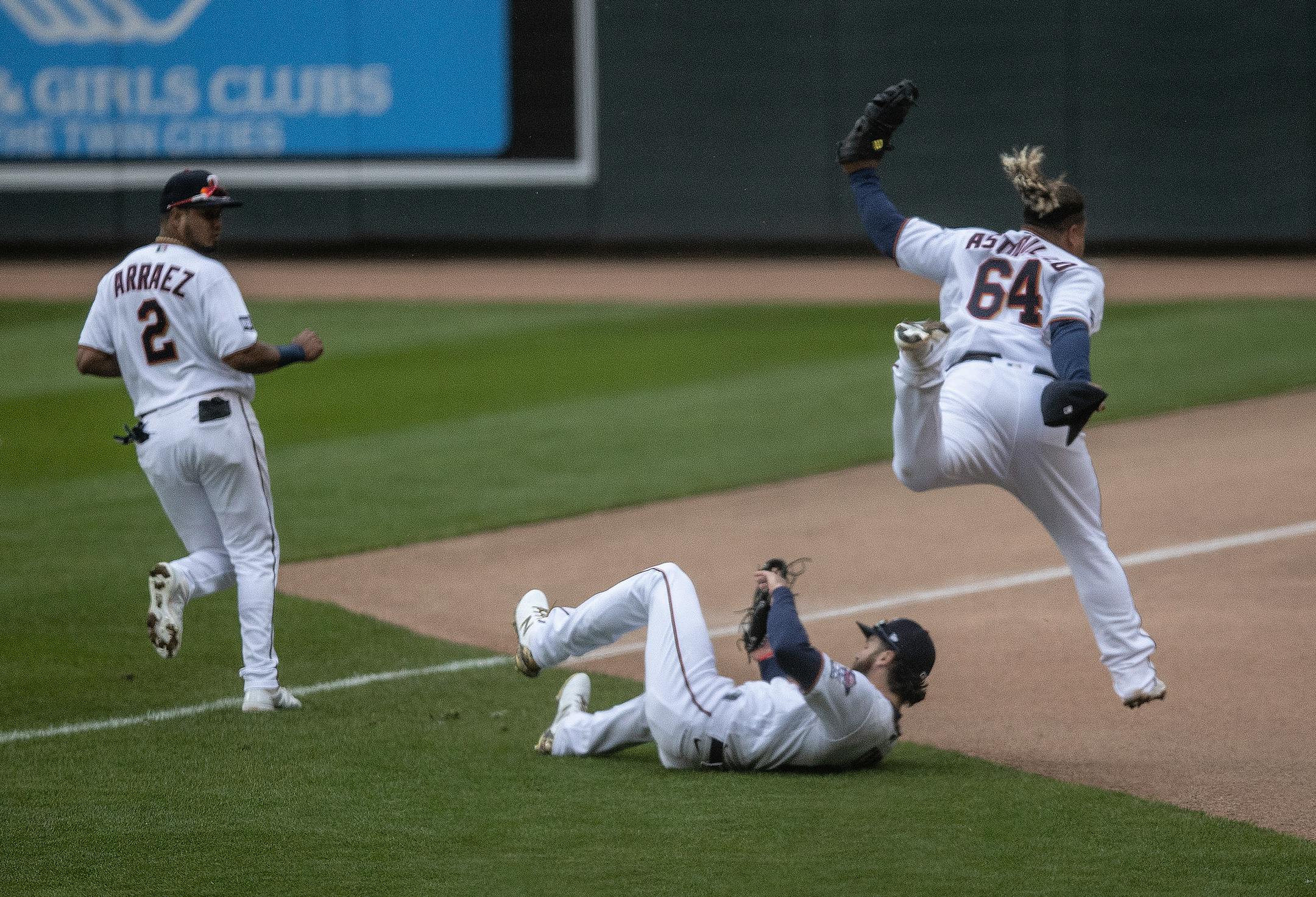Minnesota Twins catcher Willians Astudillo (64) jumped over teammate, right fielder Jake Cave (60), after he caught a foul ball hit by Pittsburgh Pirates third baseman Erik Gonzalez in the seventh inning.