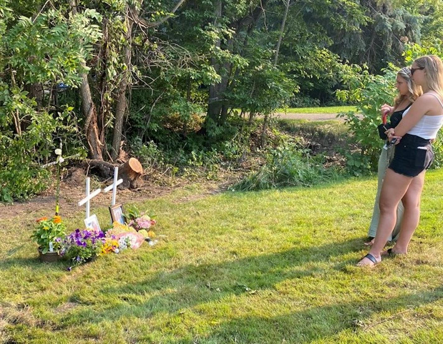 Mourners stopped by the memorial for Mack Motzko and Sam Schuneman along a busy North Shore Drive throughout Monday, leaving golf balls and hockey pucks on piles of flowers beside two white crosses. Framed photos of Motzko and Schuneman were placed next to the crosses. (Kim Hyatt/Star Tribune)