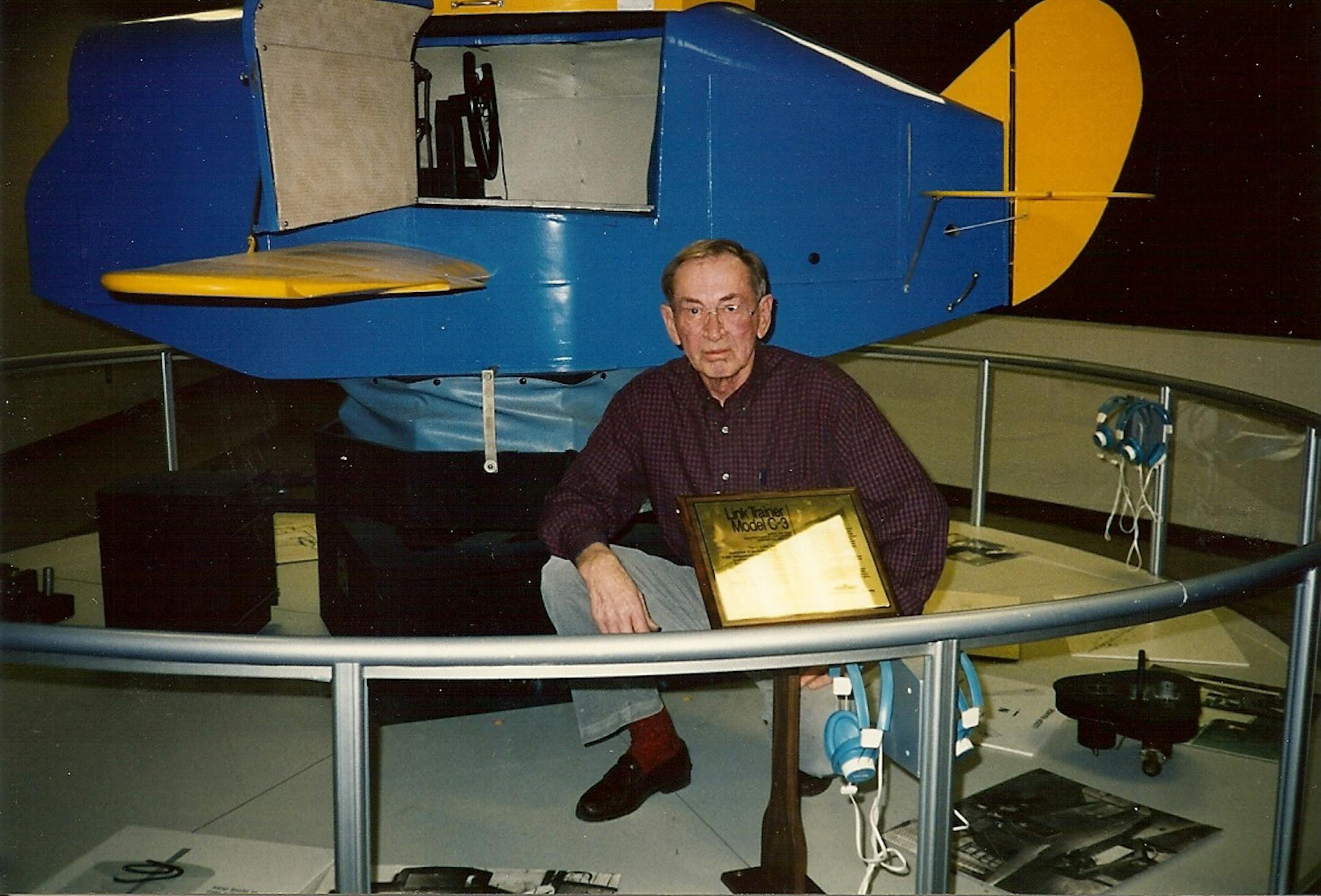 Curtis Erickson is shown with the Link trainer that he used to train commercial airline pilots on flying by instrument.