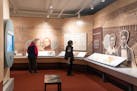 Visitors walk around the "Many Voices, Many Stories, One Place" exhibit. The exhibit includes stories from Dakota and Ojibwe people, Japanese-American